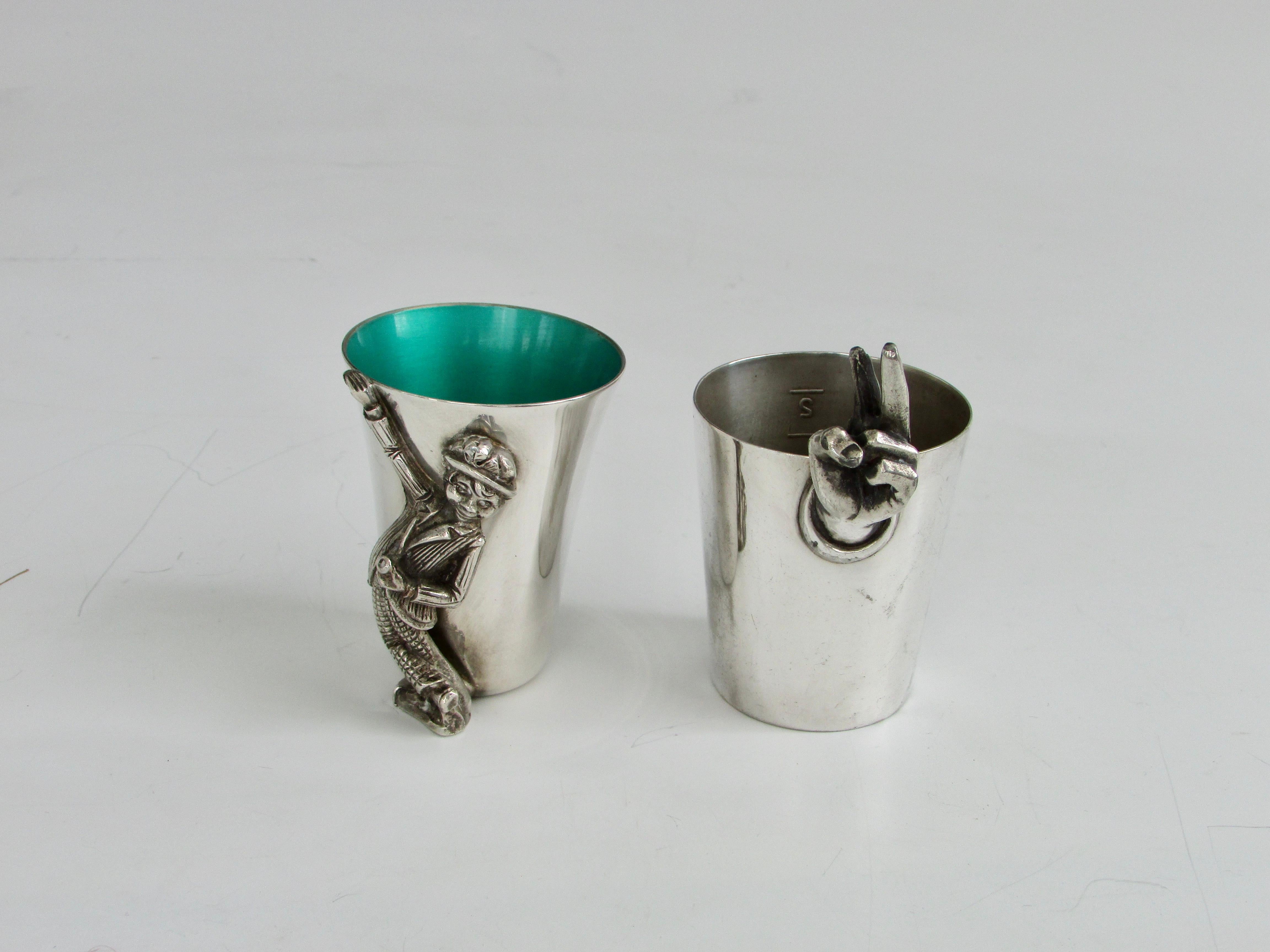 Two fingers please. Shot measure silver plate cups. One with enamel interior by Reed and Barton. With happy drunk figure. The second by Napier. Showing two fingers as measure. Priced separately.