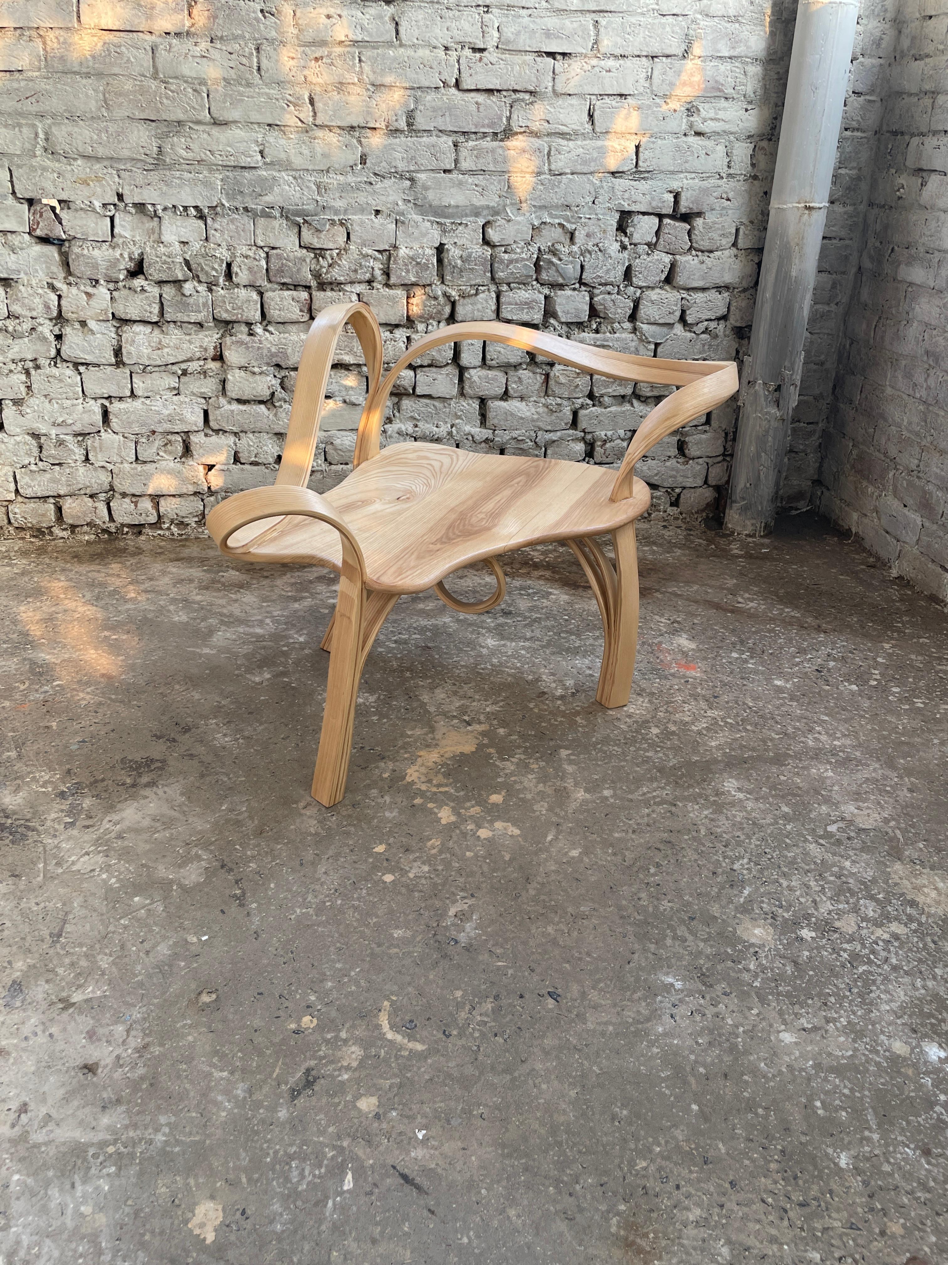 One seat is a lounge chair made in solid ashwood by bending wood. Three of the legs have been made using the wood-bending technique to adopt an abstract natural wave-like design. The design is bent around the wooden seat. The grain-revealing polish