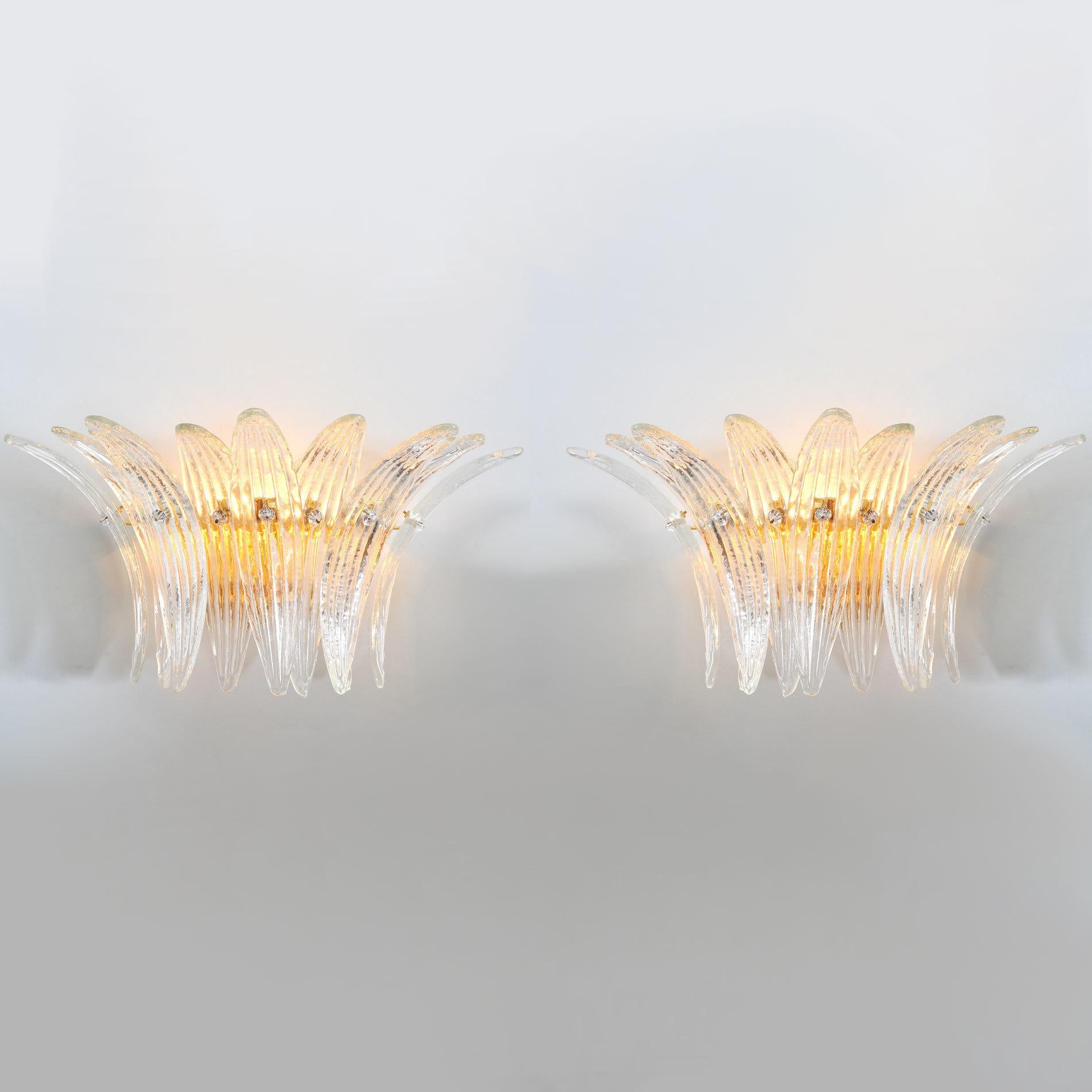 Aplique italiano con 9 hojas de cristal de Murano transparente sopladas a mano, montado en un marco de metal chapado en oro de 24 quilates de Fabio Ltd / Made in Italy
2 luces / tipo E12 o E14 / máx. 40W cada una
Medidas: Anchura 19 pulgadas /