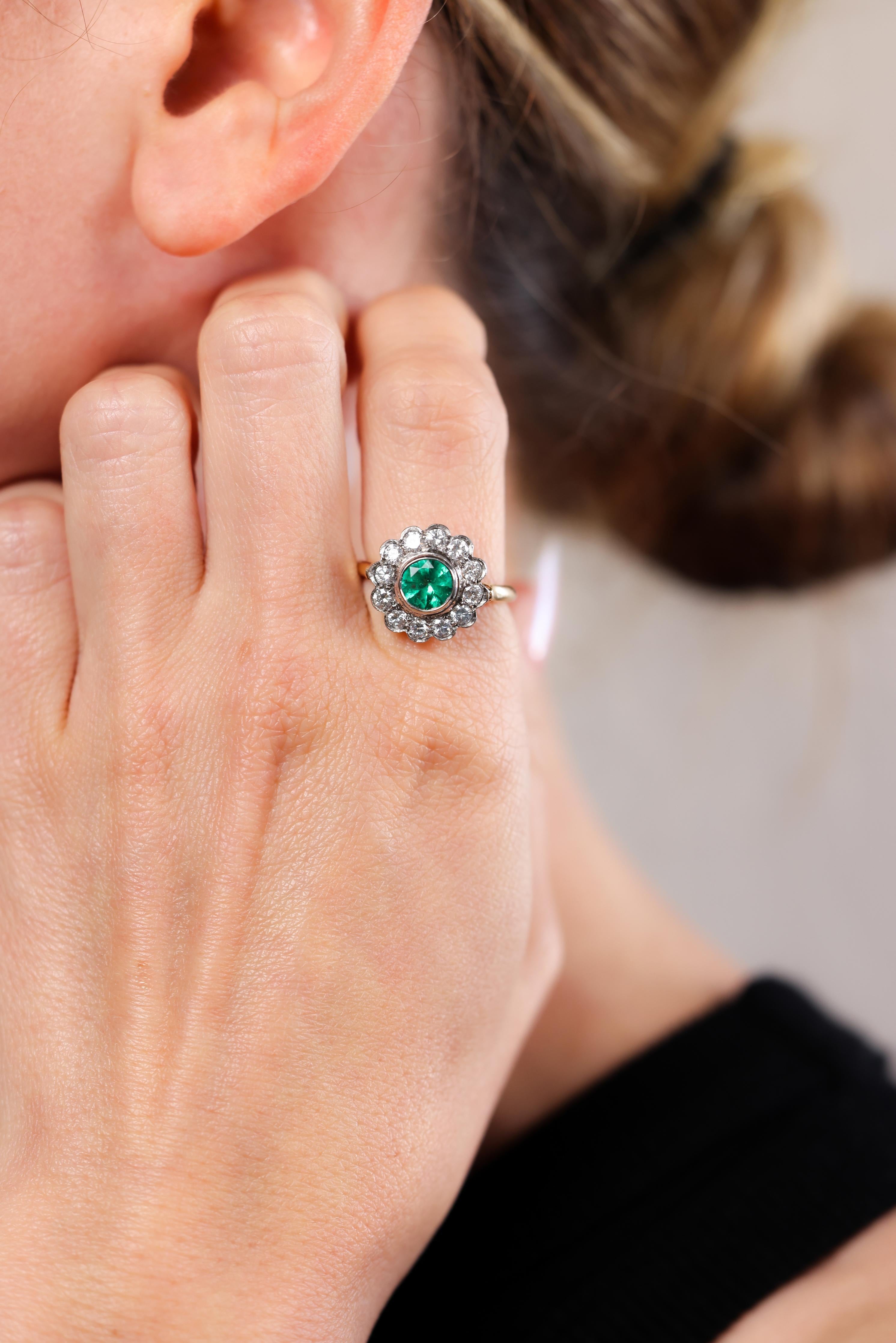 One Victorian Revival Emerald Diamond 14k Yellow Gold Platinum Cluster Ring. Featuring one round brilliant cut emerald weighing approximately 1.00 carat. Accented by 12 round brilliant cut diamonds with a total weight of approximately 1.00 carat,