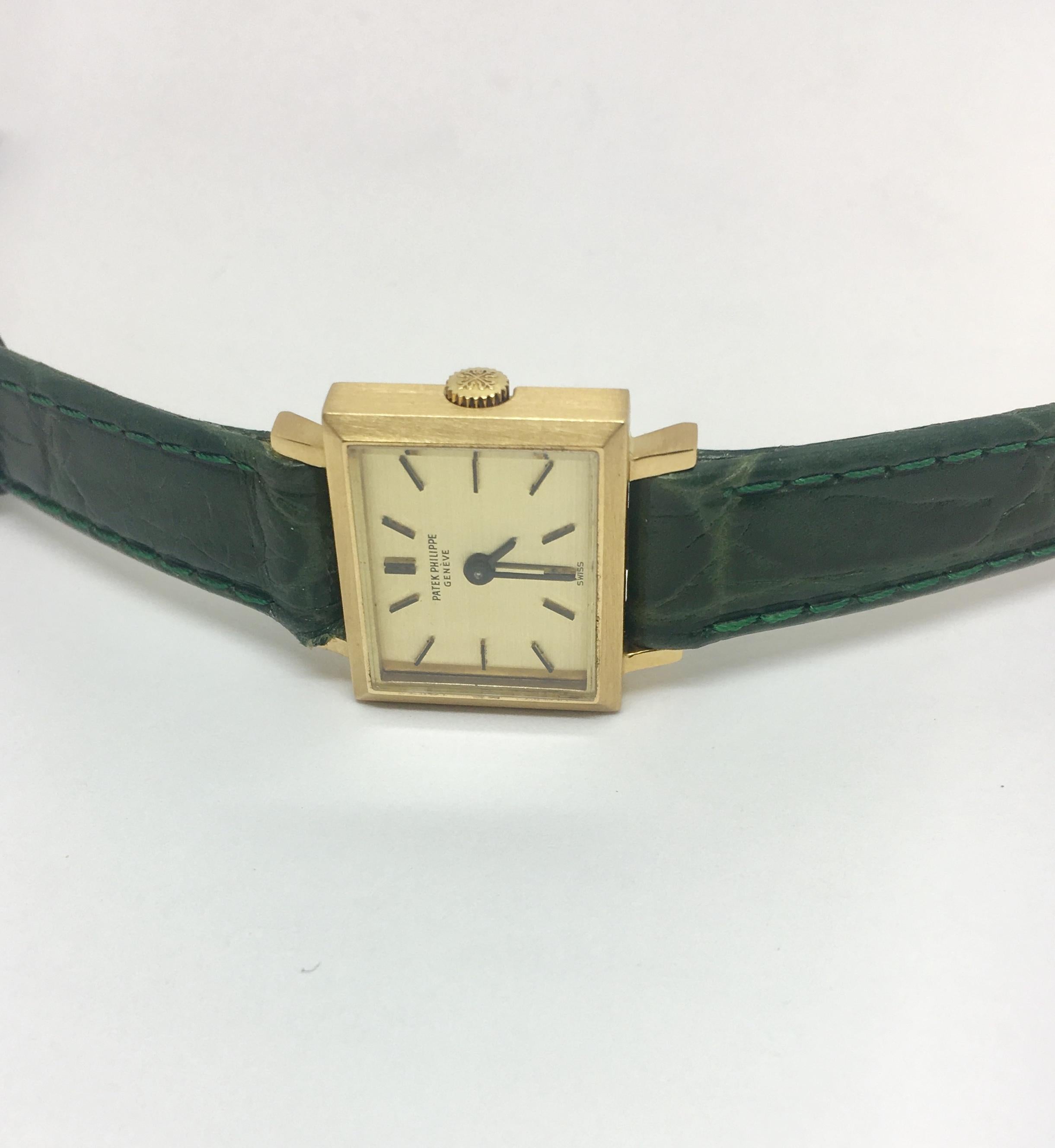 One Patek Philippe 20mm time piece,  18kt yellow gold rectangular case, the approximate inside wrist measurement is 7.25 inches,  the olive green leather watch strap compliments this piece. Circa 1980's
