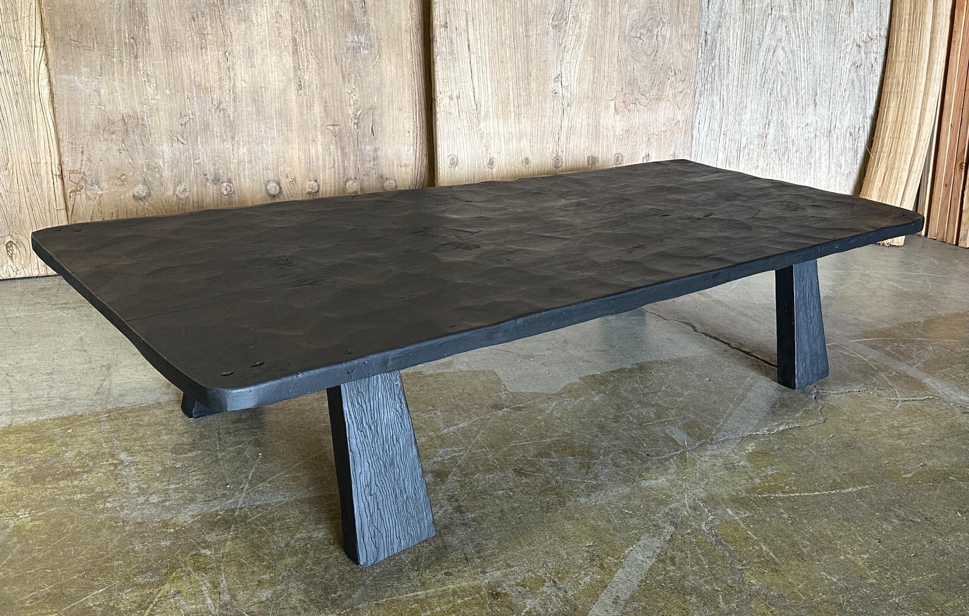 This coffee table consists of a 19th c, hand hewn (with a machete), one wide board top. The table has been refinished in a black finish, still allowing the natural wood and patina to show. It shows some age appropriate wear, but has a sturdy