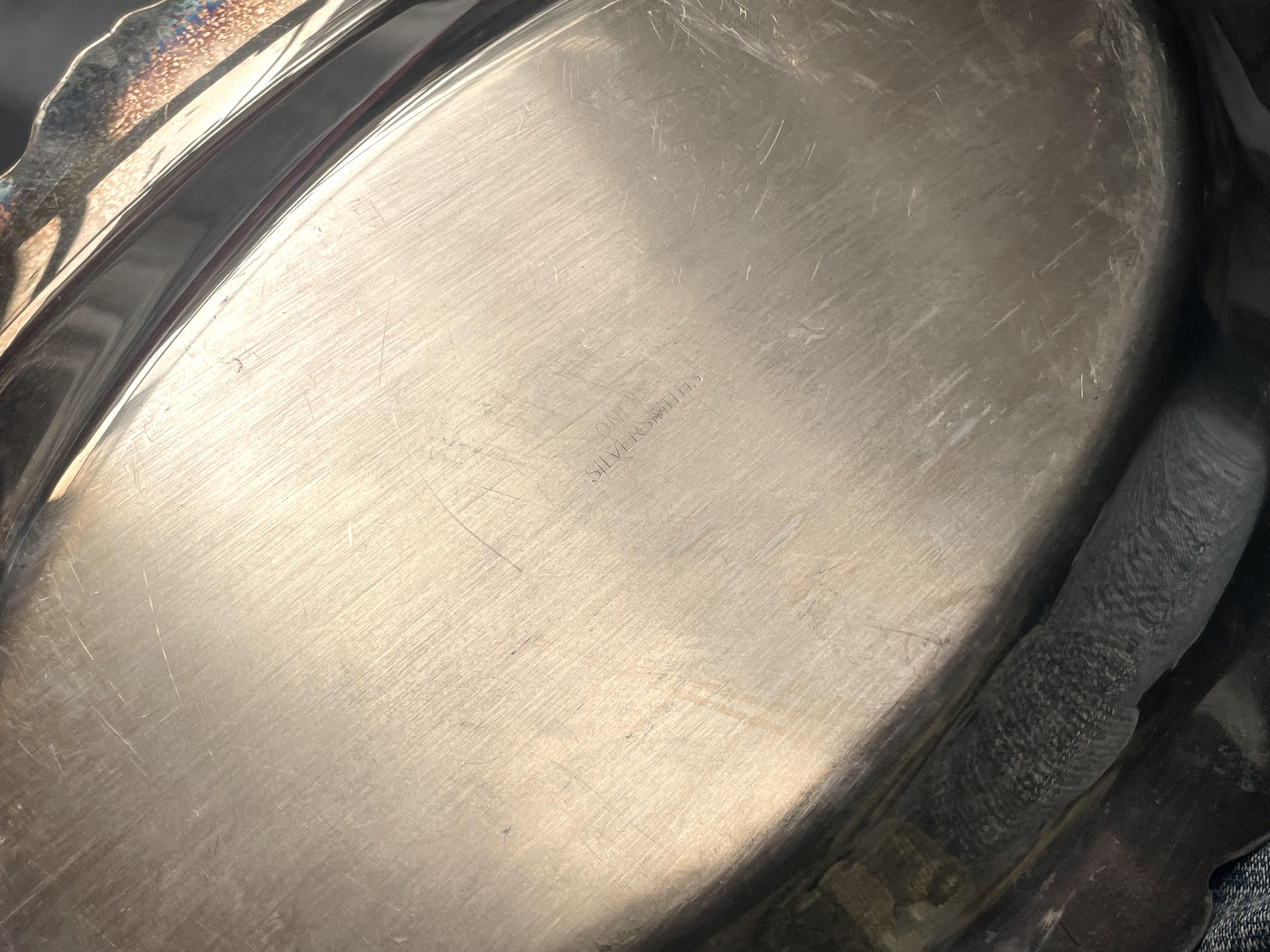 Il s'agit d'un joli plat ovale en métal argenté avec un large rebord et un motif de tourbillon répétitif en relief sur le pourtour. Le plat mesure 14 1/4 pouces de large et 7 1/2 pouces dans l'autre direction. Le bol impressionné mesure 10 pouces de