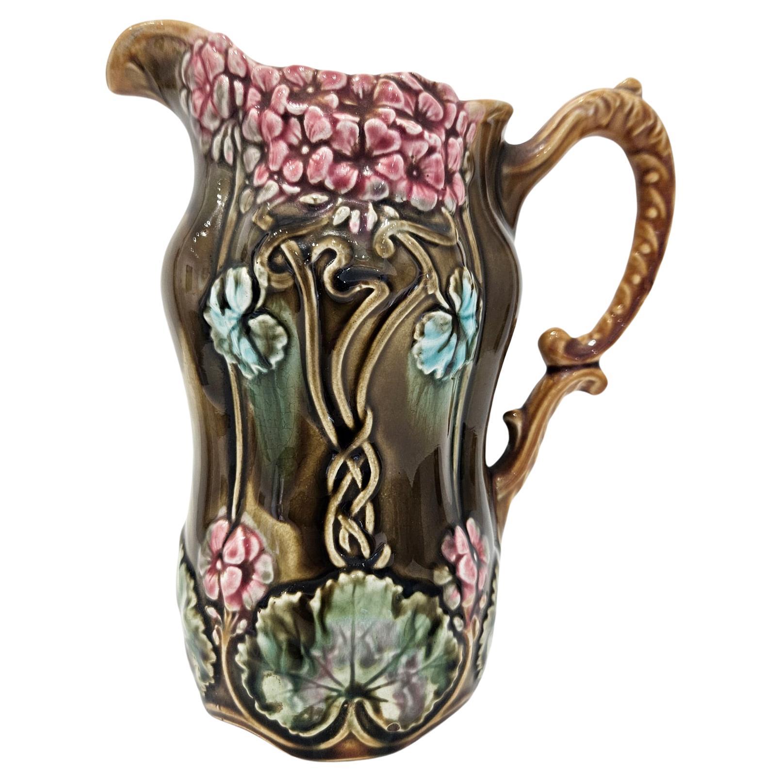 A bright and colourful Art Nouveau Majolica pitcher made by Frie Onnaing in northern France in c. 1880. 

This design is known as Coligny, and features a combination of groups of hydrangea and intertwined vines in art nouveau designs across the