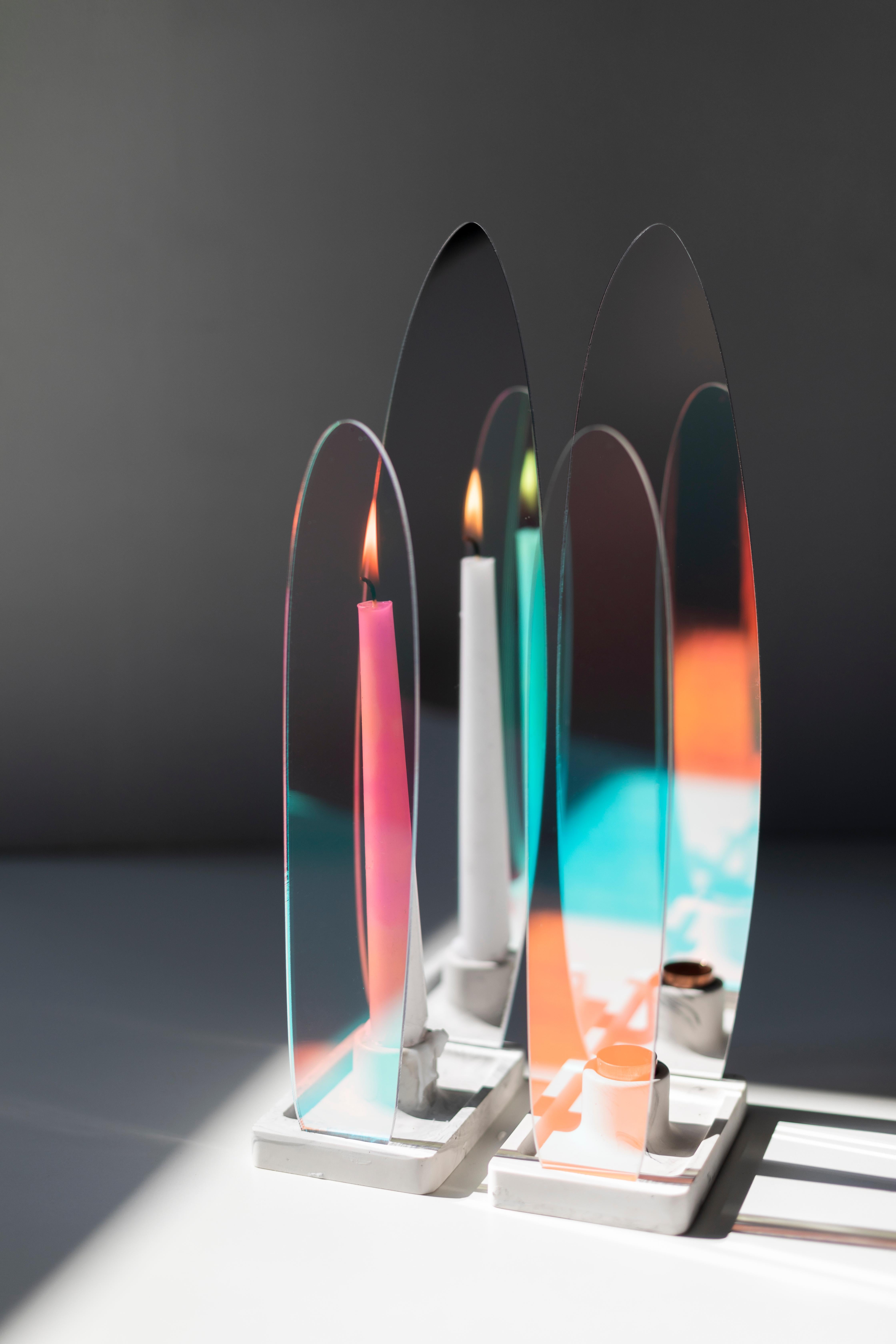L'opera mostra uno spettacolo ipnotico di ombre colorate in continua evoluzione. La sua forma si ispira a quella della fiamma di una candela: asimmetrica, mutevole eppure così viva. Il portacandele è progettato per candele a bastoncino di 20 mm di
