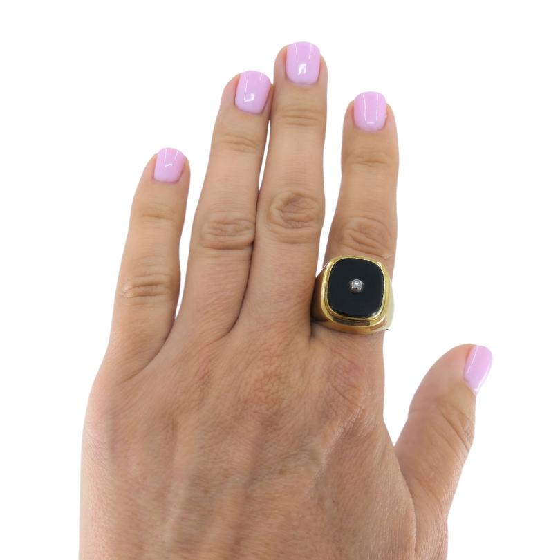 This onyx and 14k gold men's vintage signet ring has a grounded, confident feel with just enough detail to keep it interesting. The ring features a rectangular face inlaid with a polished onyx. A little bezel-set diamond is placed in the center. The