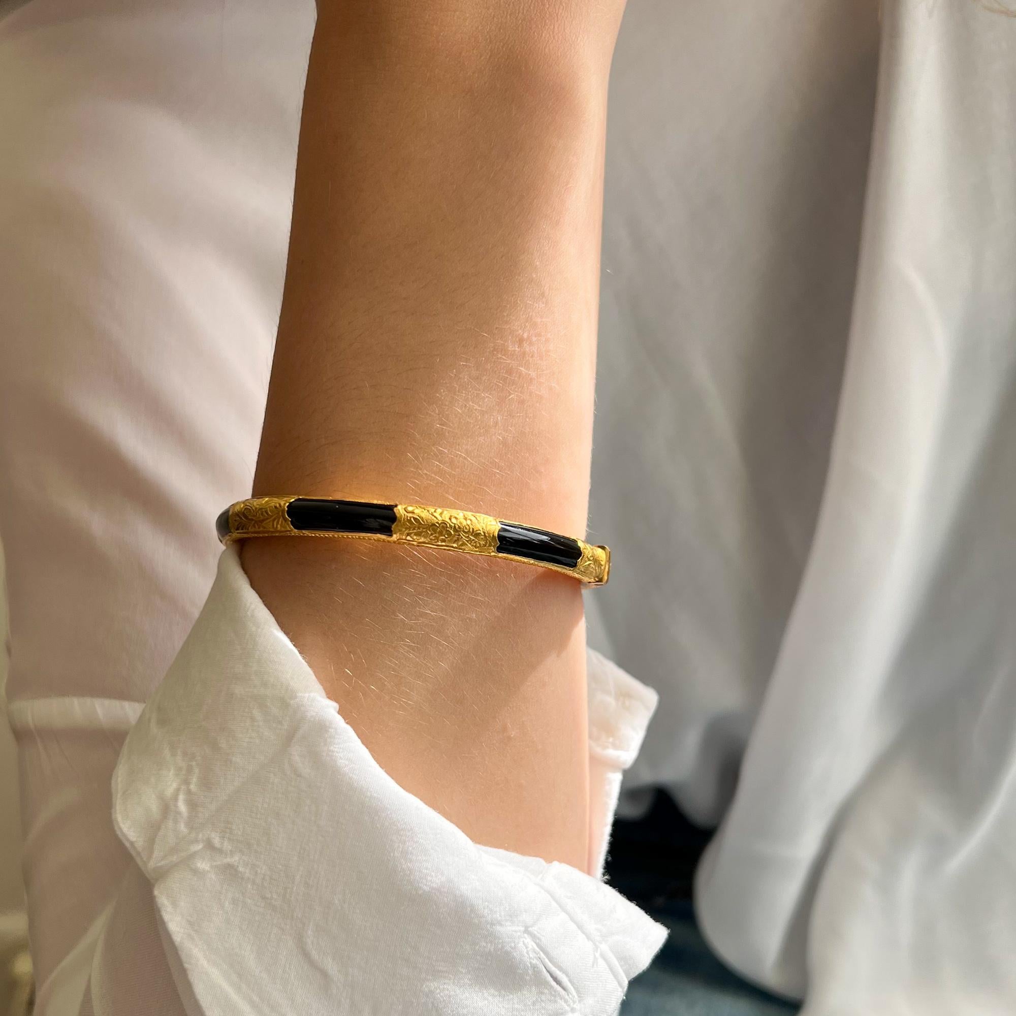 A bangle bracelet with a beautiful combination of onyx and warm yellow gold. This 20 karat gold bangle bracelet has six floral engraved compartments with flowers and leaf design. Between the gold six black onyx sections accentuates the engraved 20
