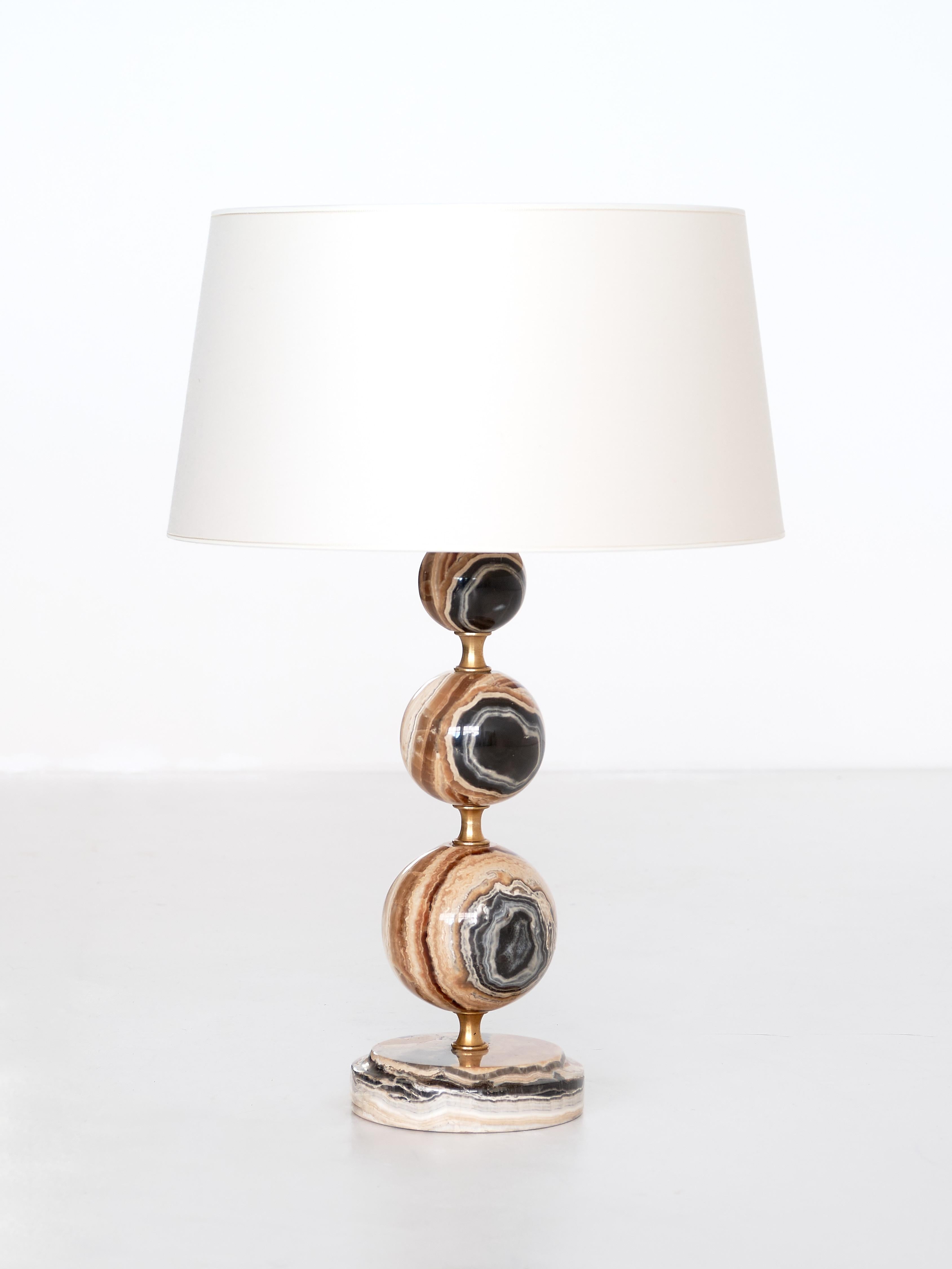 This elegant table lamp was produced in Italy in the late 1970s. The stacked base consists of three onyx spheres and four brass rings, resting on a circular onyx foot. The contrasting veins of the brown, white and black onyx give the lamp a refined