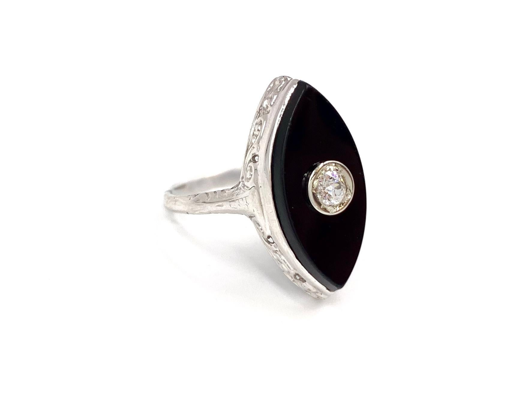 Circa 1950's this unique and fun 14 karat white gold ring features a marquise shaped slice of black onyx with a single bezel set old European cut diamond center. Diamond has an approximate weight of .10 carats at approximately G color, SI1 clarity.
