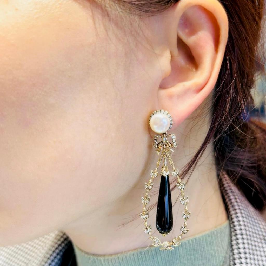 Estos pendientes de gota de ónix y perlas estilo Art Déco combinan la elegancia clásica con un atrevido aire vintage. Una luminosa perla redonda se asienta en el lóbulo de la oreja, mientras que una elegante gota de ónice cuelga con gracia en el