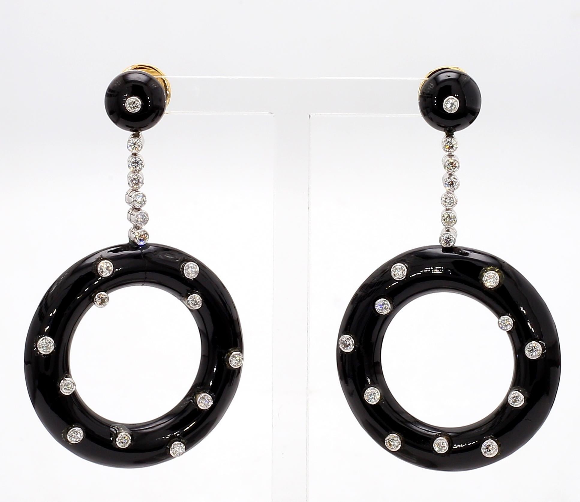 The earrings are a striking creation featuring black onyx as the primary stone. Embellished with sparkling diamonds, these Art Deco style earrings exude elegance. The design showcases a circular onyx centerpiece, adorned with diamonds, suspended