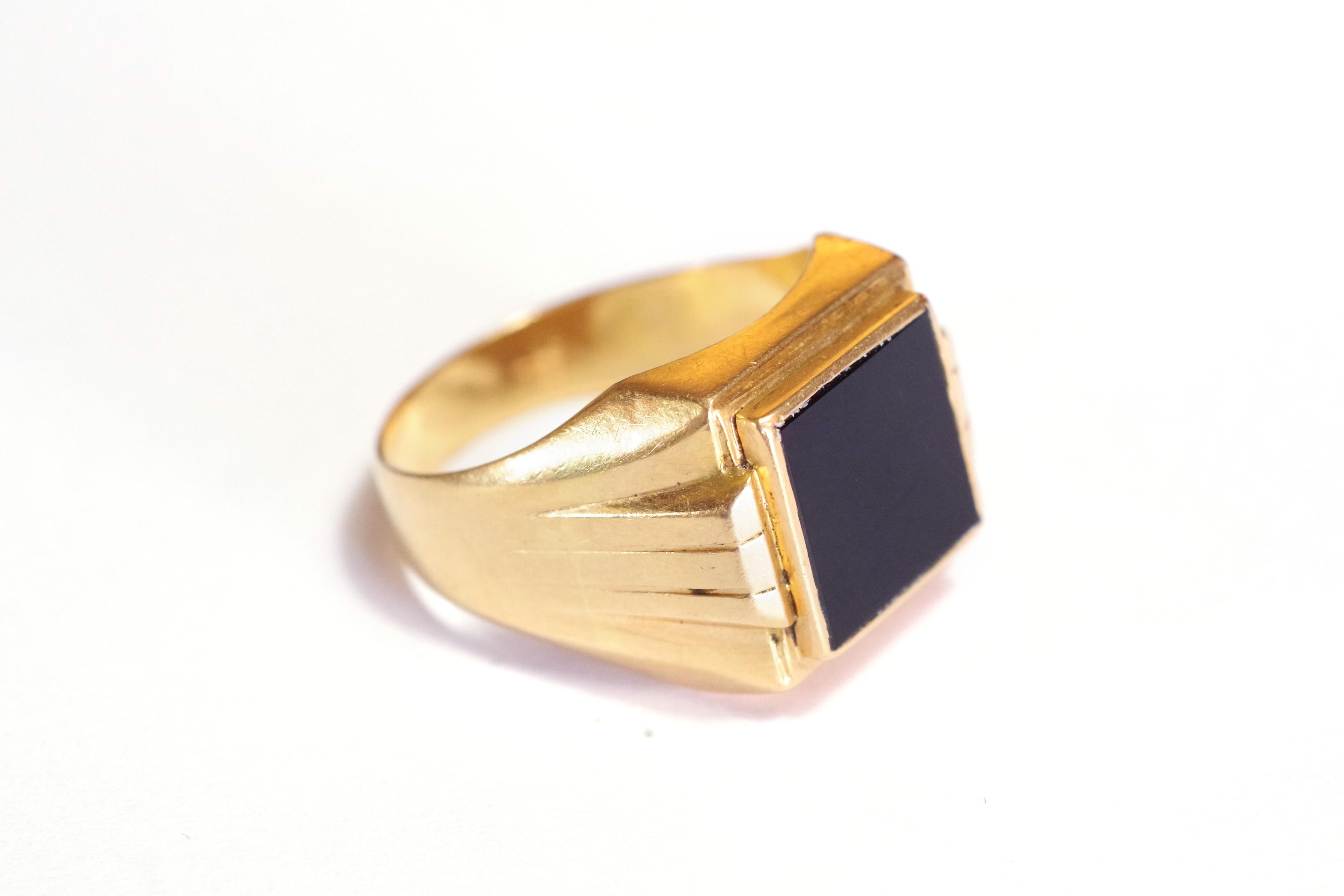 Onyx Art Deco signet ring in 18 karat rose gold. The ring is set with a square onyx plate in closed setting in a very good condition. The shoulders of the ring are decorated with geometric shapes from the Art Deco style. Ring from the
