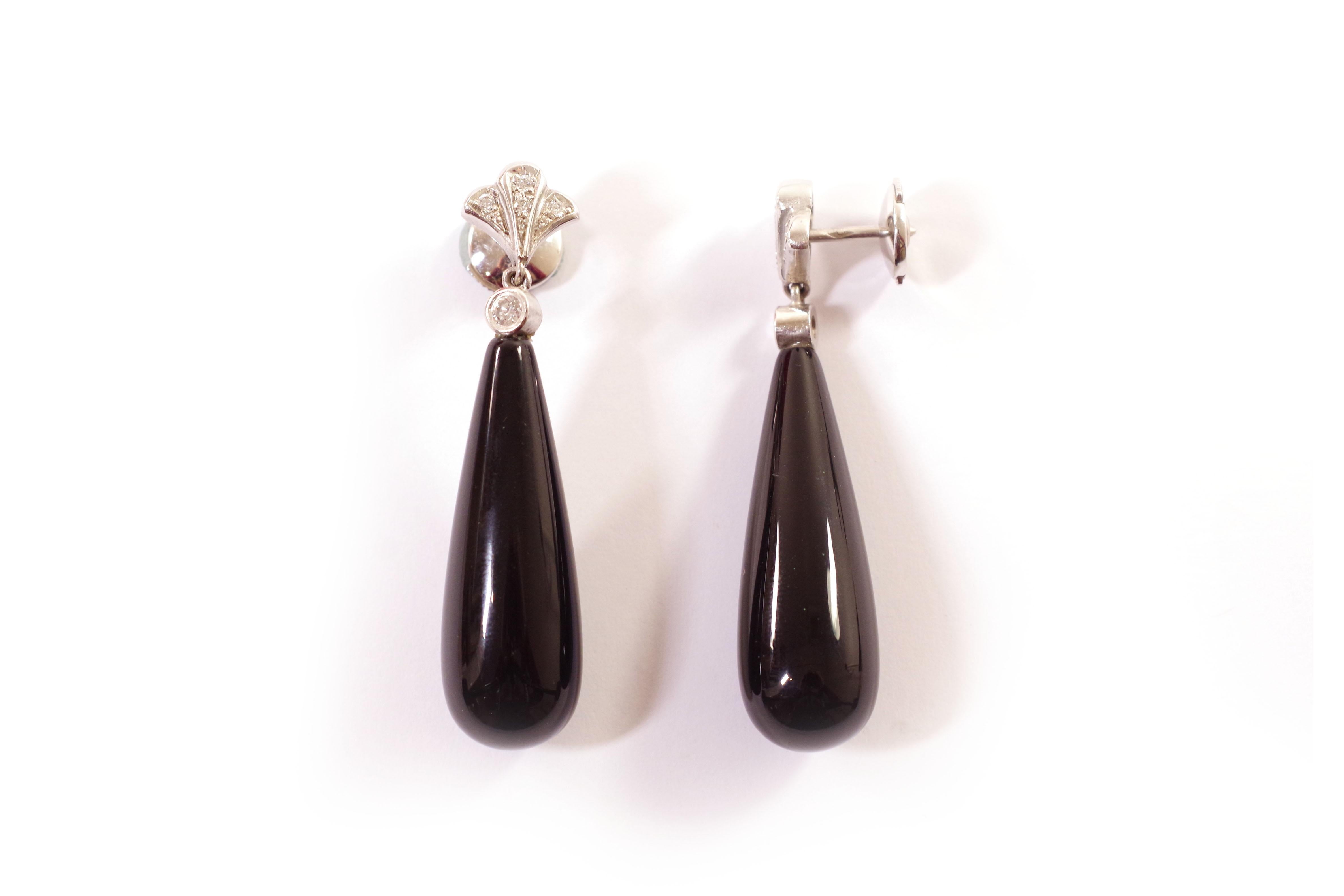 Onyx Art Deco style earrings in white gold 18 karats. Pair of long earrings, each of which is decorated with a large onyx drop topped by a brilliant-cut diamond and an Art Deco motif in white gold set with four diamonds. Pair of earrings, French, in