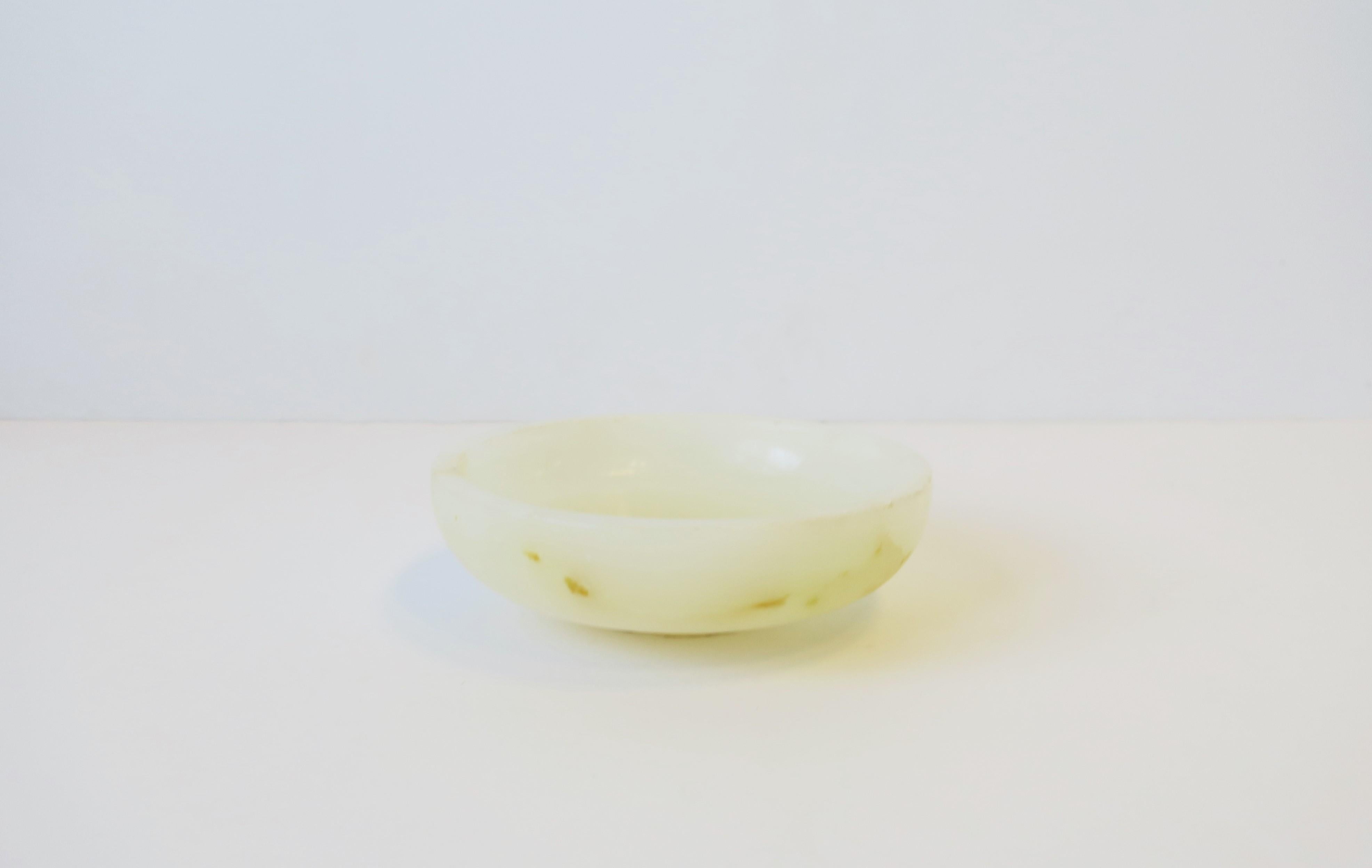 A white to off-white onyx dish or bowl in the modern style, circa 1970s, 20th century. A great standalone piece or as a vide-poche (catch-all) for coin change or jewelry (as demonstrated.) Bowl measures: 5.5