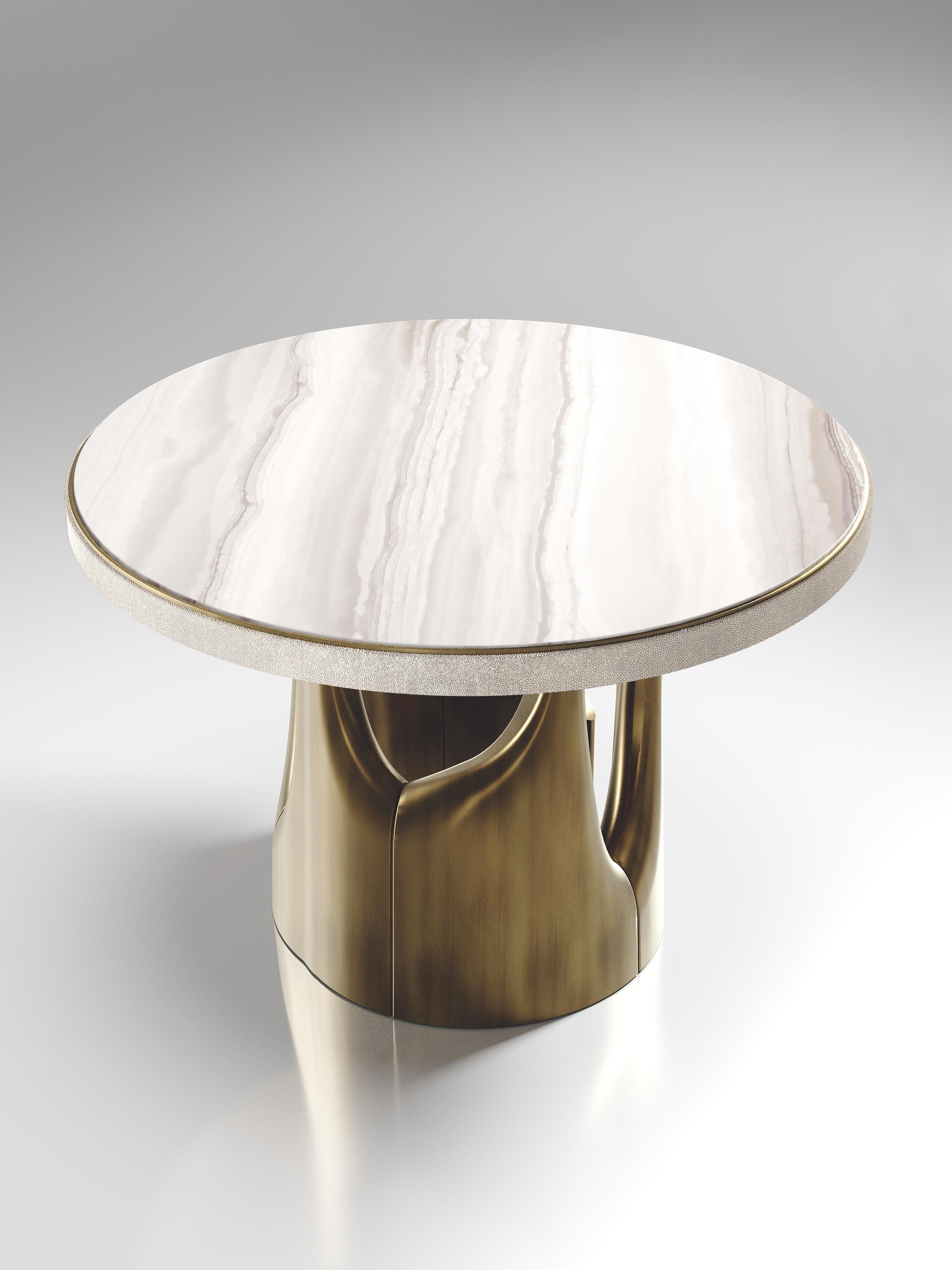 The triptych breakfast table by R&Y Augousti is a stunning multi-faceted sculptural piece. The beautiful hand craved details on the bronze-patina base demonstrate the incredible artisan work of Augousti. The top is in a cream onyx with a cream