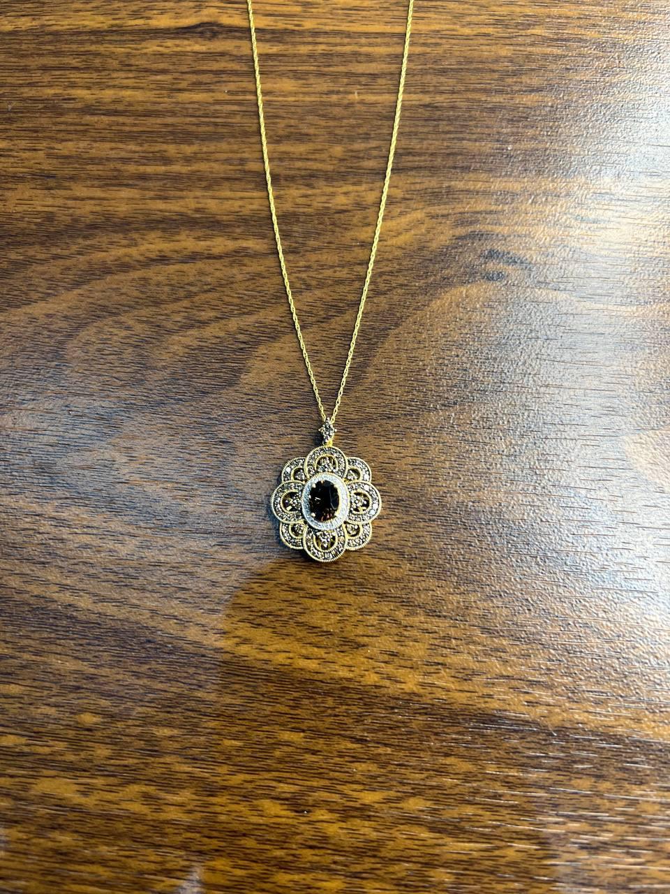 Explore the refined beauty of this exquisite pendant necklace.
Crafted with intricate detailing, the necklace features a delicate chain that gracefully holds a floral-inspired pendant.
The pendant showcases ornate filigree work surrounding a central