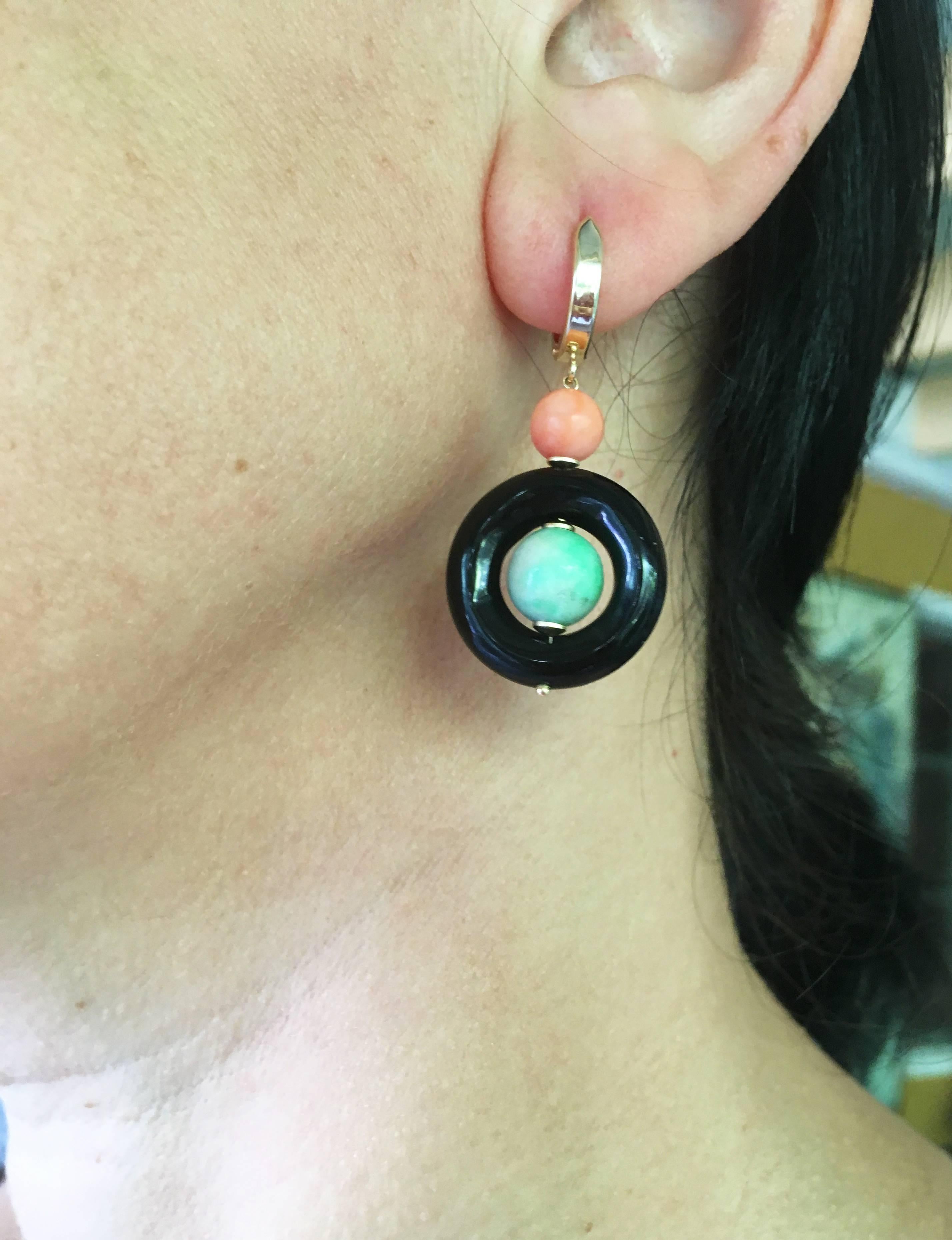 These double tiered earrings are dramatic with a bold onyx circle bead. The opposing pale coral pink and green jade beads make for a striking design. The earrings are highlighted with 14k yellow gold wiring and lever backs. These earrings hang at