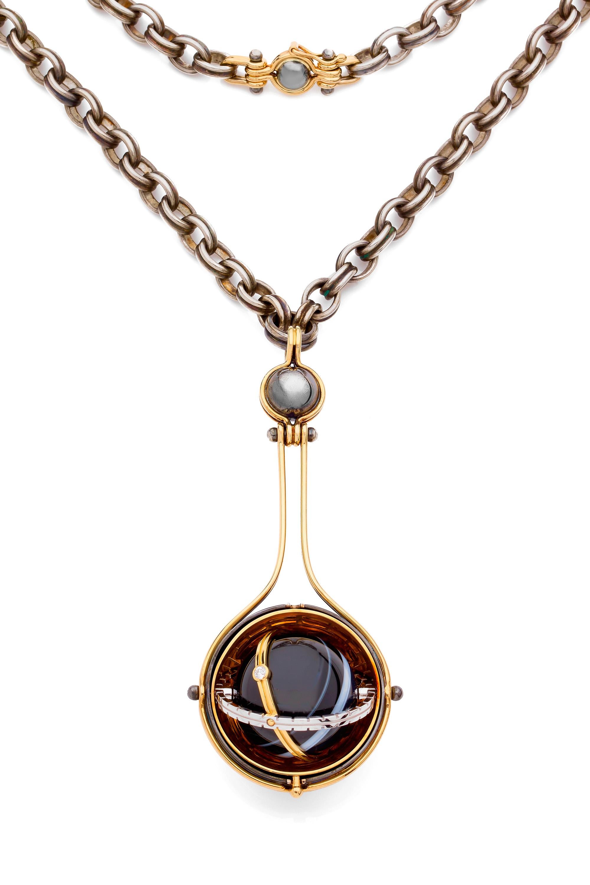 Yellow gold and distressed silver pendant. Rotating sphere revealing an onyx planet, encircled by white gold ring and yellow gold ring, set with a diamond.  

Distressed silver chain.

Details:
Onyx Nicolo: ø 23mm
Diamonds: 0,06 cts
18k Yellow Gold: