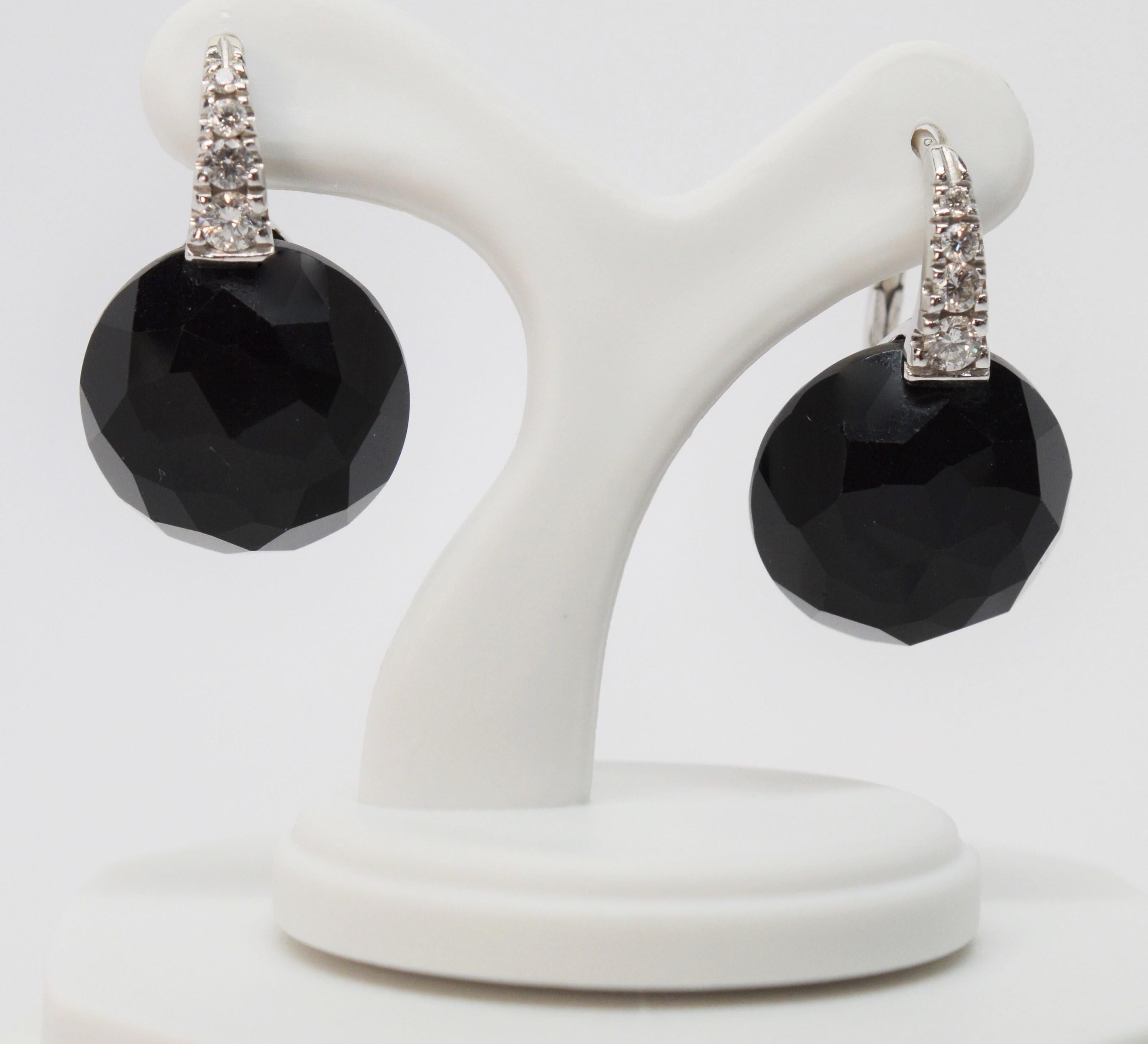 Enjoy the impact of a modern style drop earring pair with classic black and white characteristics. Bright full cut round diamonds, .26 carat total weight, adorned the eighteen karat leaver back stems that lead to facet cut black onyx 14mm cabochon