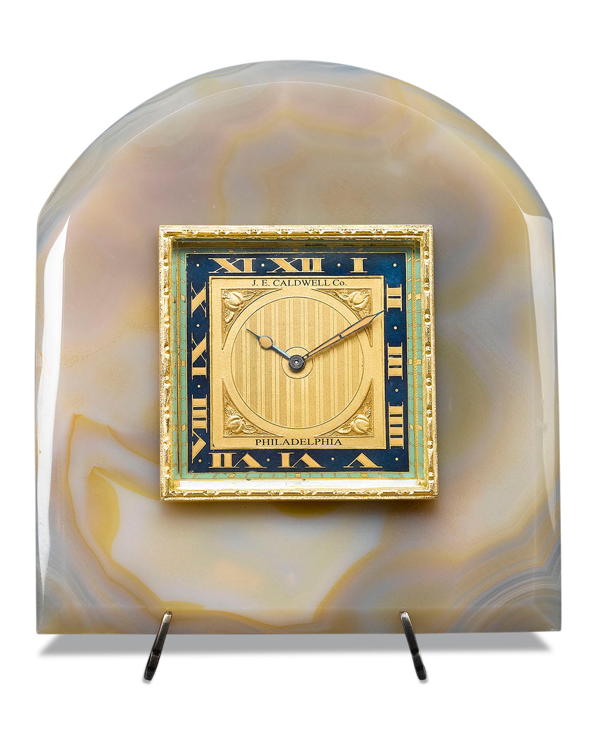 The Art Deco style is beautifully executed in this enchanting desk clock by J.E. Caldwell. The gilded dial, beautifully enameled in midnight blue and celadon green, sports four perfect apples in relief at its corners, and is framed by a luxurious