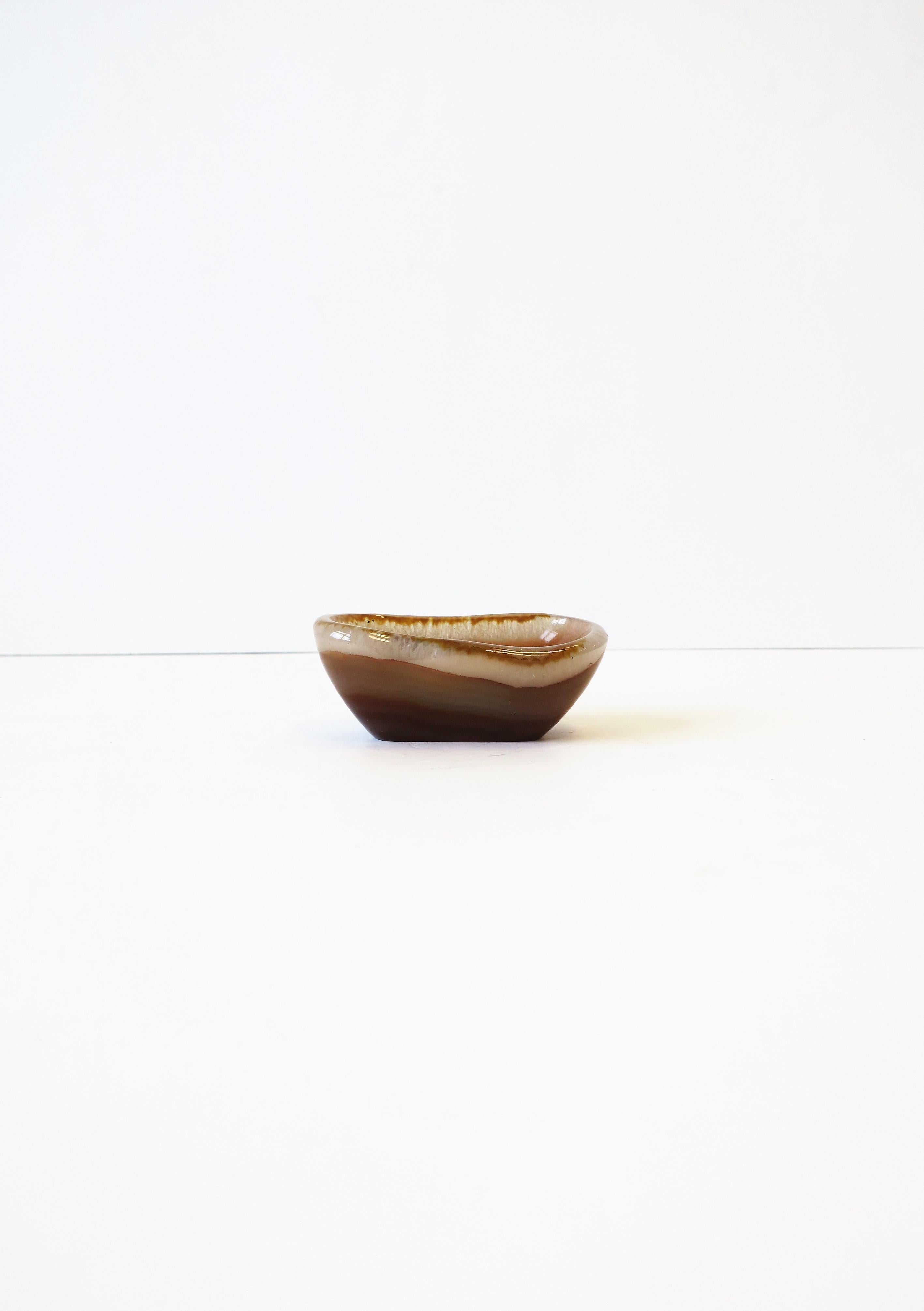 A small and substantial white and caramel colored onyx dish or small bowl/vessel. Piece can work as a small jewelry dish or a desk accessory for small items, etc. Elegant and convenient for a table, office desk, vanity, nightstand, etc. 

Piece