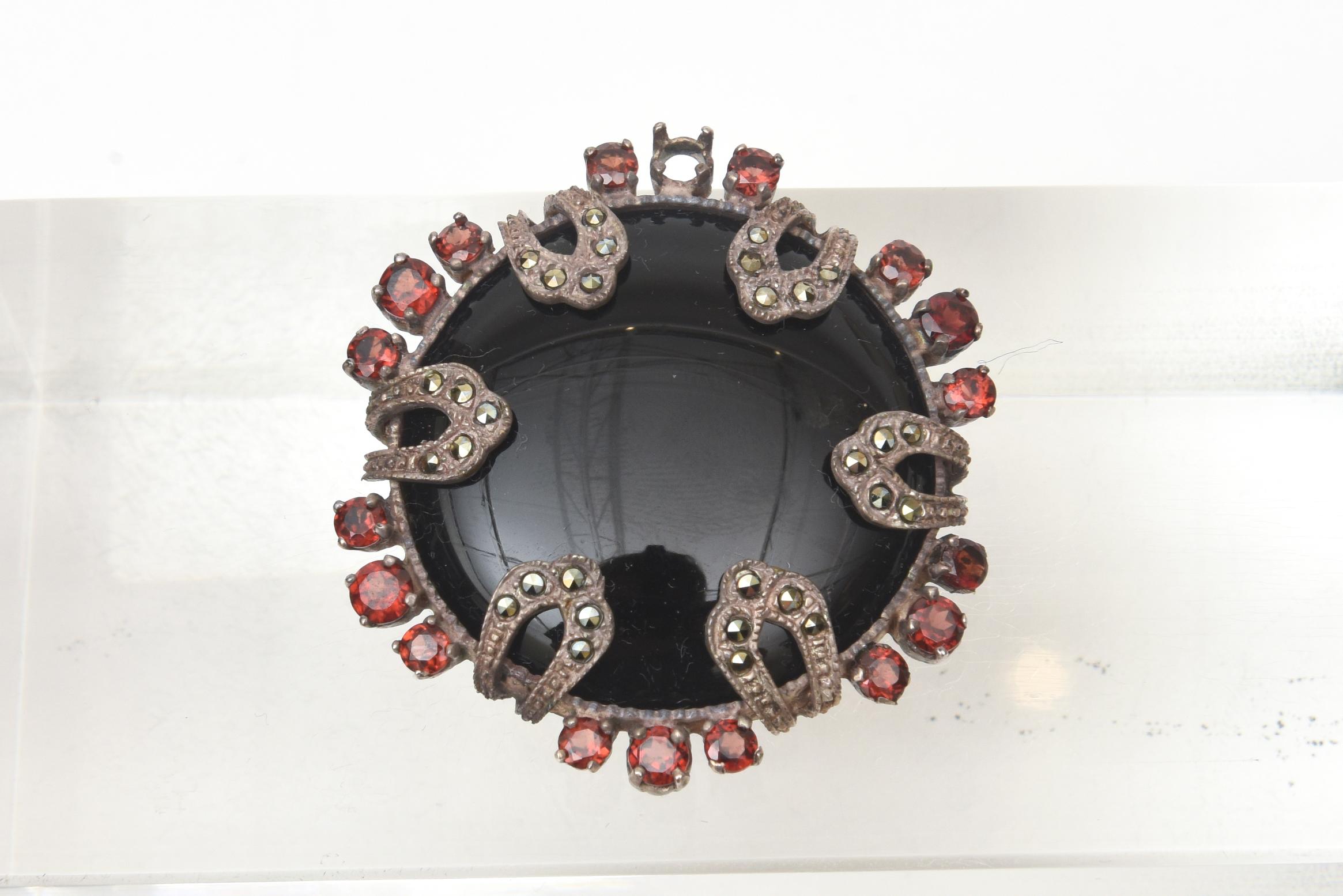 This gorgeous small but stately art deco pin / brooch is black onyx, surrounding garnets, sterling silver and marquisette. It is marked 925 MT. It will adorn any great lapel of a jacket of blouse. it is elegant and timeless. From the 30's. 

