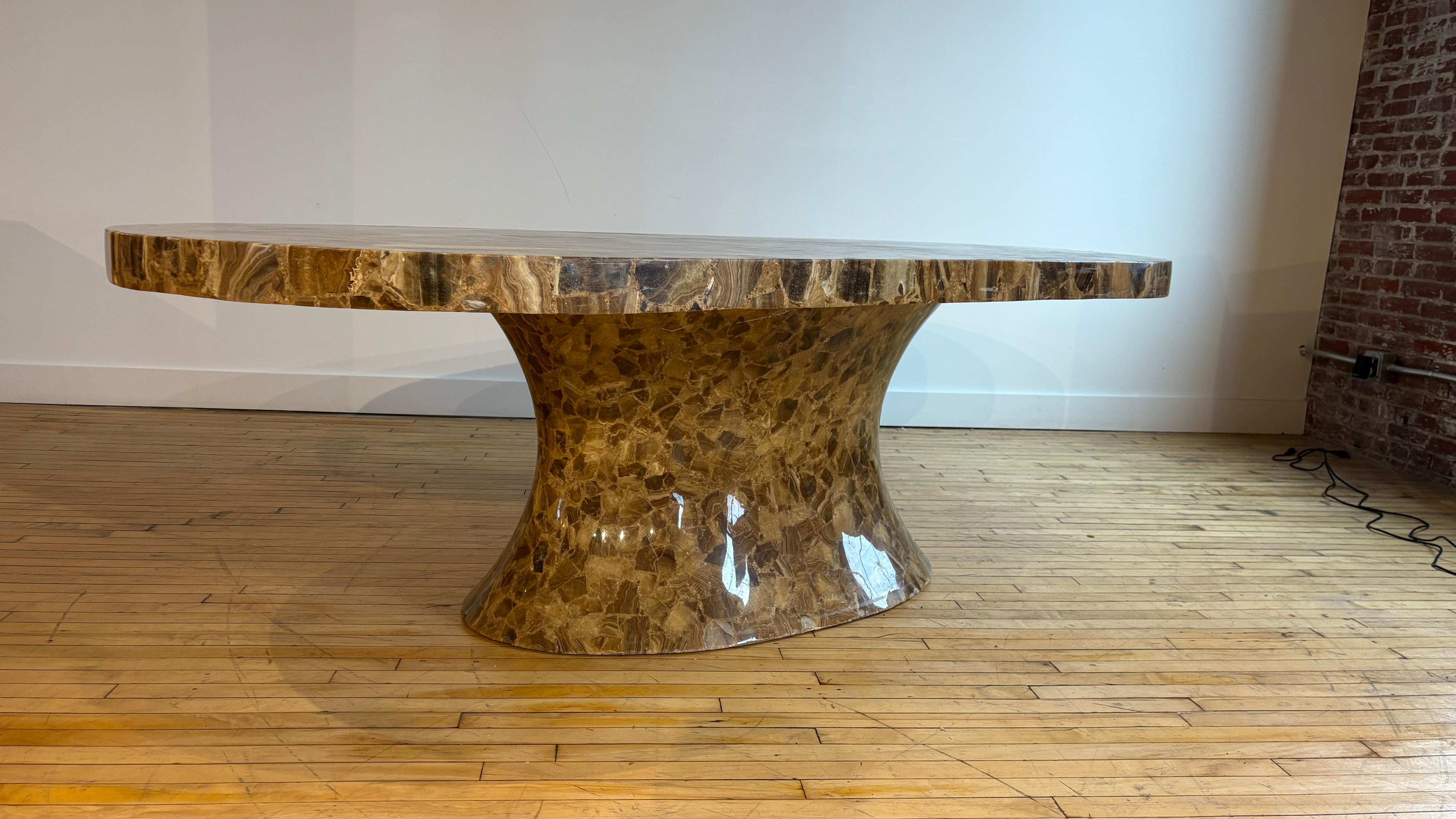 Superbe et rare table de salle à manger ou de conférence ovale en Oynx marron plaqué Muller's of Mexico, fabriquée à la main dans les années 1980, sur une base sculptée en forme de piédestal. 

Le plateau est composé de tranches de placage d'onyx