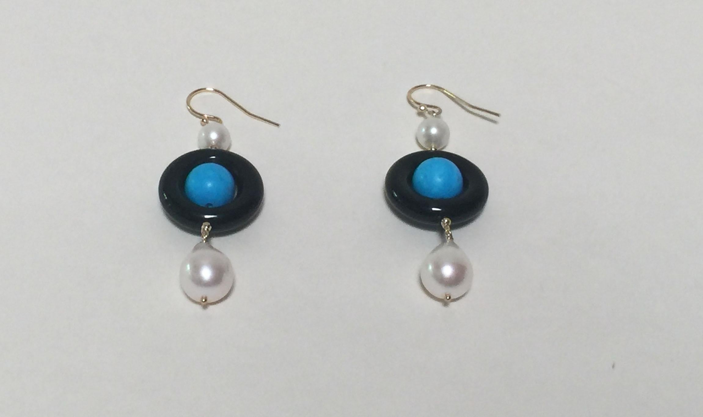 These elegant onyx, pearl and turquoise earrings are highlighted with 14k yellow gold beads and wiring. The center bright blue turquoise bead is outlined by a circular black onyx bead. A small glowing white round pearl hangs above the onyx bead,