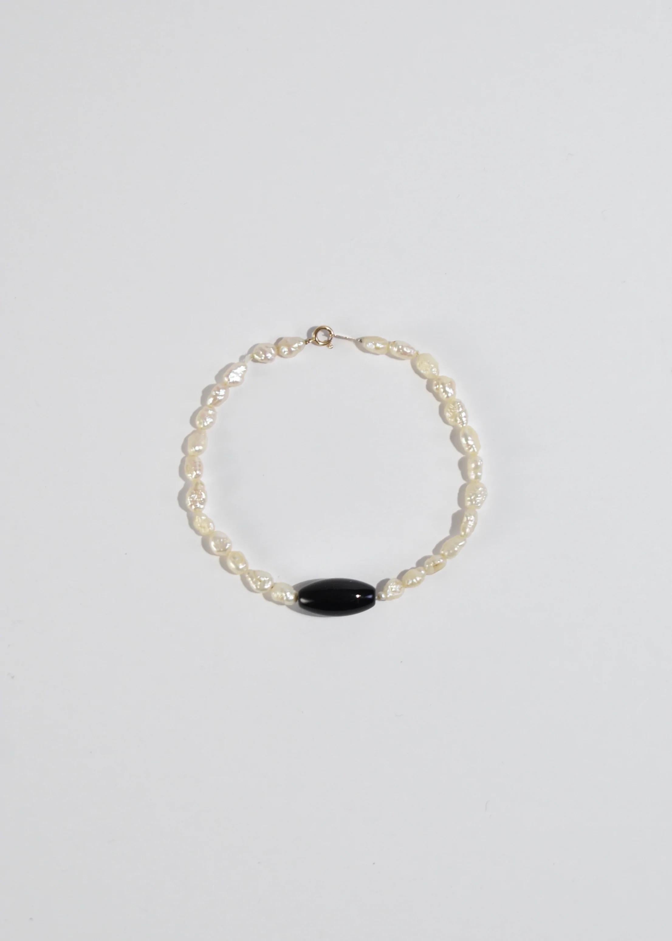 Vintage petite freshwater pearl bracelet with onyx stone detail and gold clasp closure. Stamped ﻿14k﻿.

Material: 14k gold, pearl, onyx.