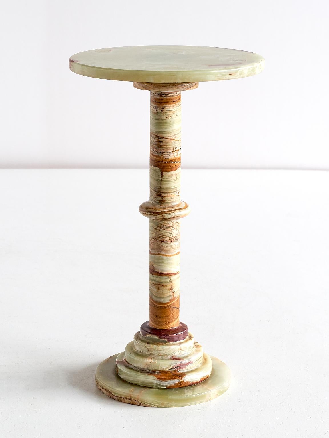 This elegant side table was produced in Italy in the 1960s. The pedestal base and top are all made of multicolored onyx. The different hues and intensities of red, white and green give the table a refined and striking appearance.