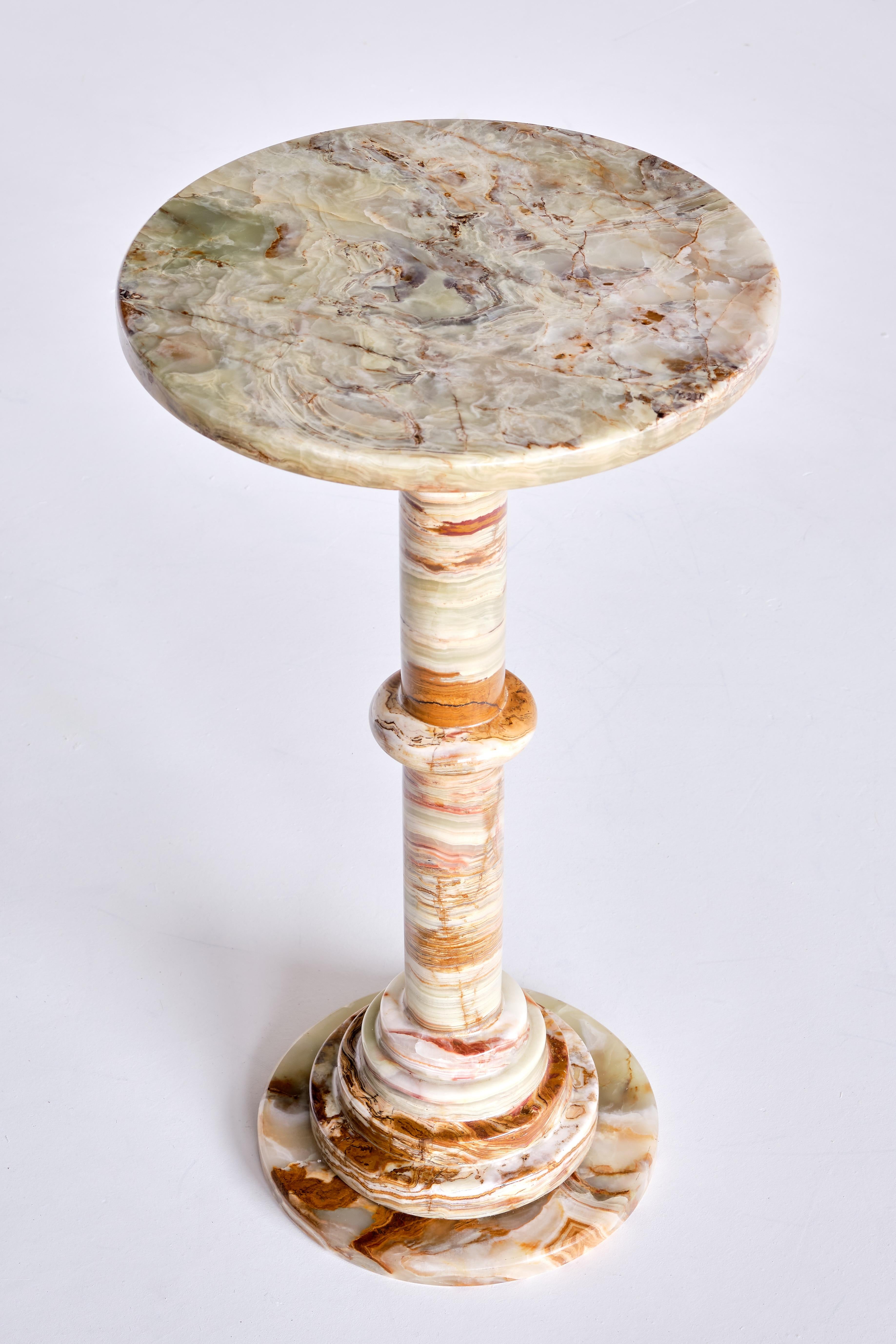 This elegant side table was produced in Italy in the 1960s. The pedestal base made of circular stacked discs and the round top are all made of solid multicolored onyx. The different hues and intensities of red, white and green give the table a