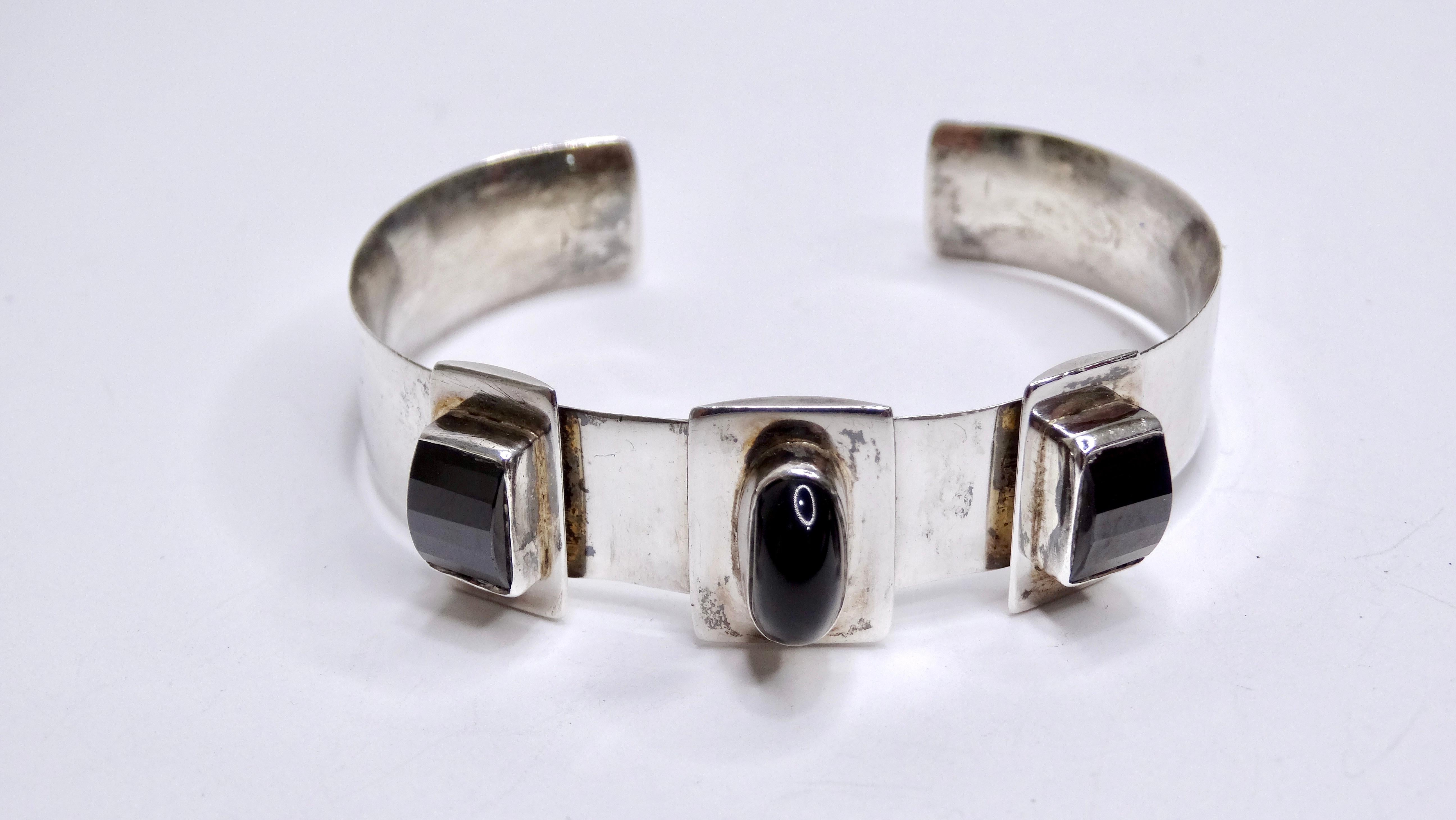 An amazing piece for a jewelry collector. Made of silver with three beautiful Onyx stones placed on the band. An oval cut stone is centered and paired with two rectangular cut stones. This modern and sleek bracelet would pair perfectly with Mugler