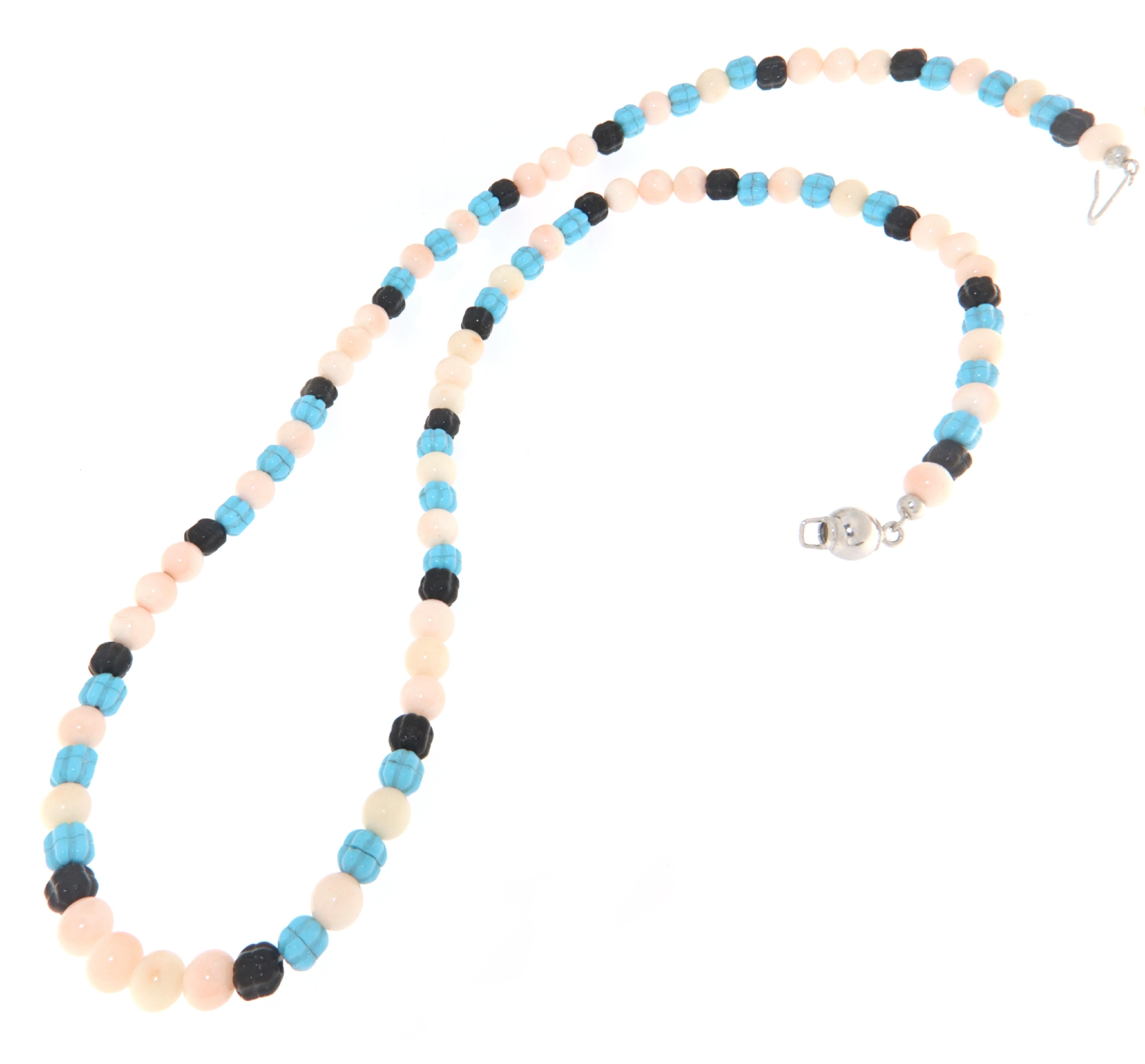 Diese Halskette mit einem Verschluss aus 925er Sterlingsilber stellt eine Harmonie von Farben und MATERIALEN dar und kombiniert auf elegante Weise rosa Koralle, schwarzen Onyx und leuchtenden Türkis. Die Abfolge der farbigen Perlen schafft einen