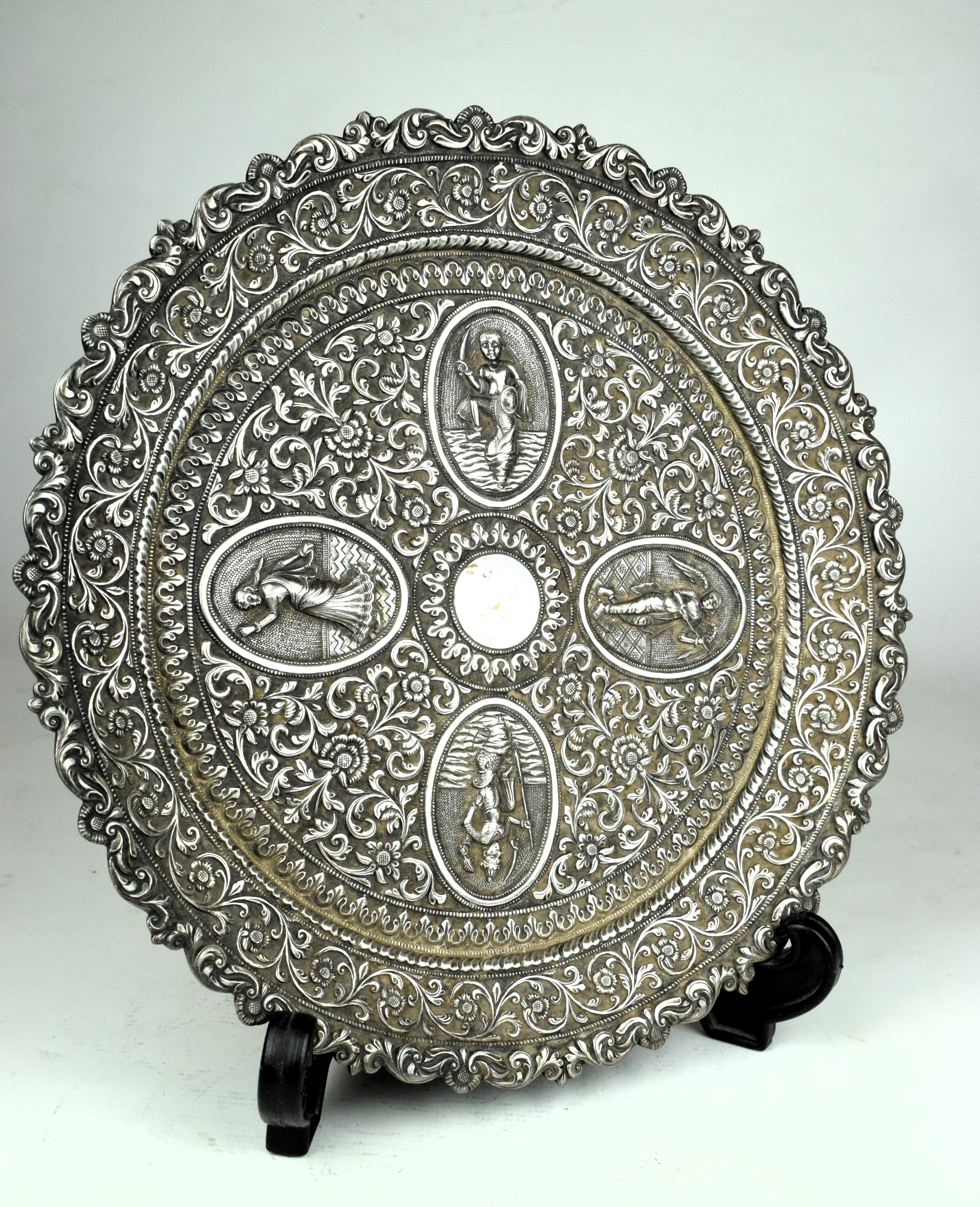 This 19th Century rare Indian Oomersi Mawji,  hand-crafted silver round tray is an exquisite work of craftsmanship. The tray depicts Hindu deities within four medallions typical of Kutch work from the region. The tray bears the makers mark 