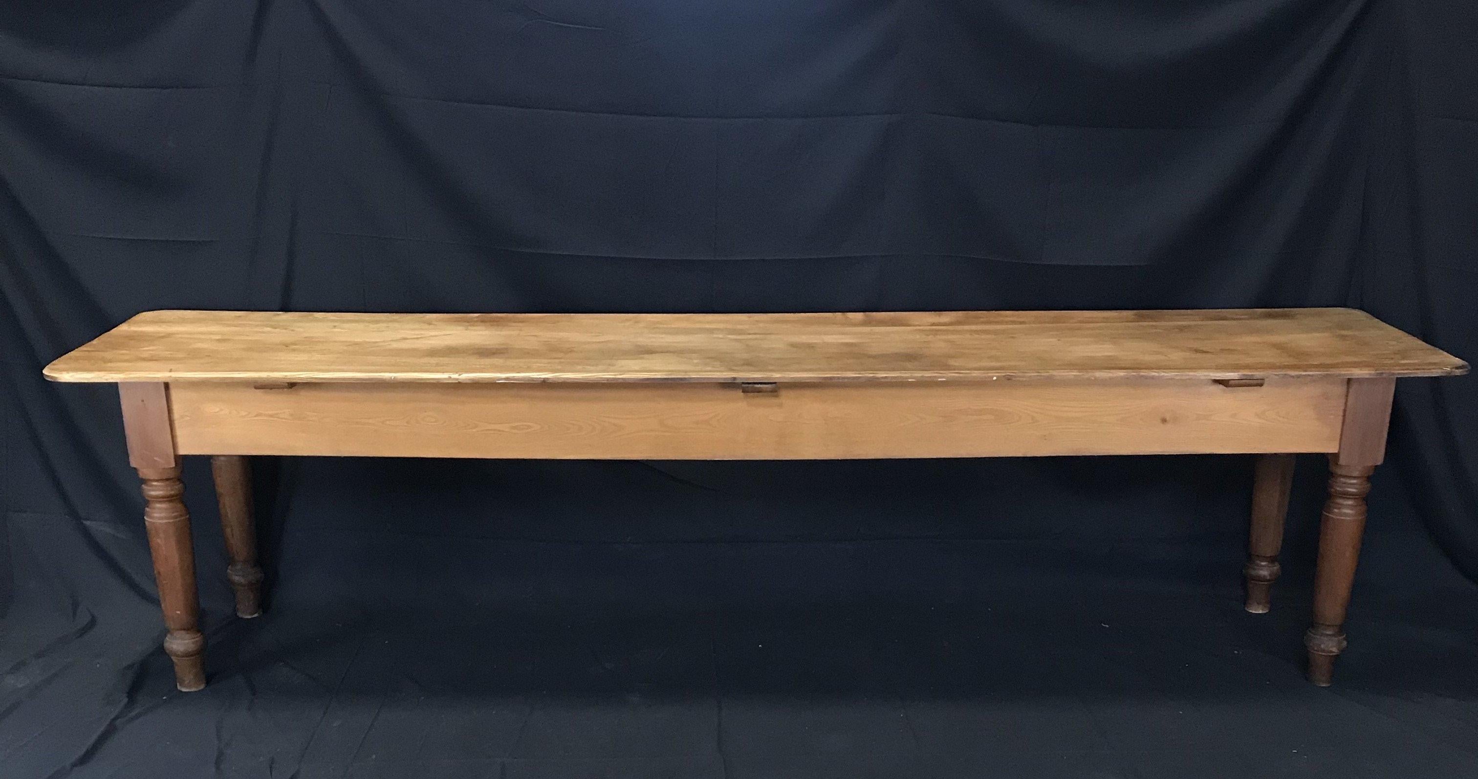 A rare find in this supremely long 19th century French pine farmtable having peg and hole joinery and charming turned legs. It will comfortably seat 12 people. Wooden pegs on top in spots on the end (see photos). Very stable and full of