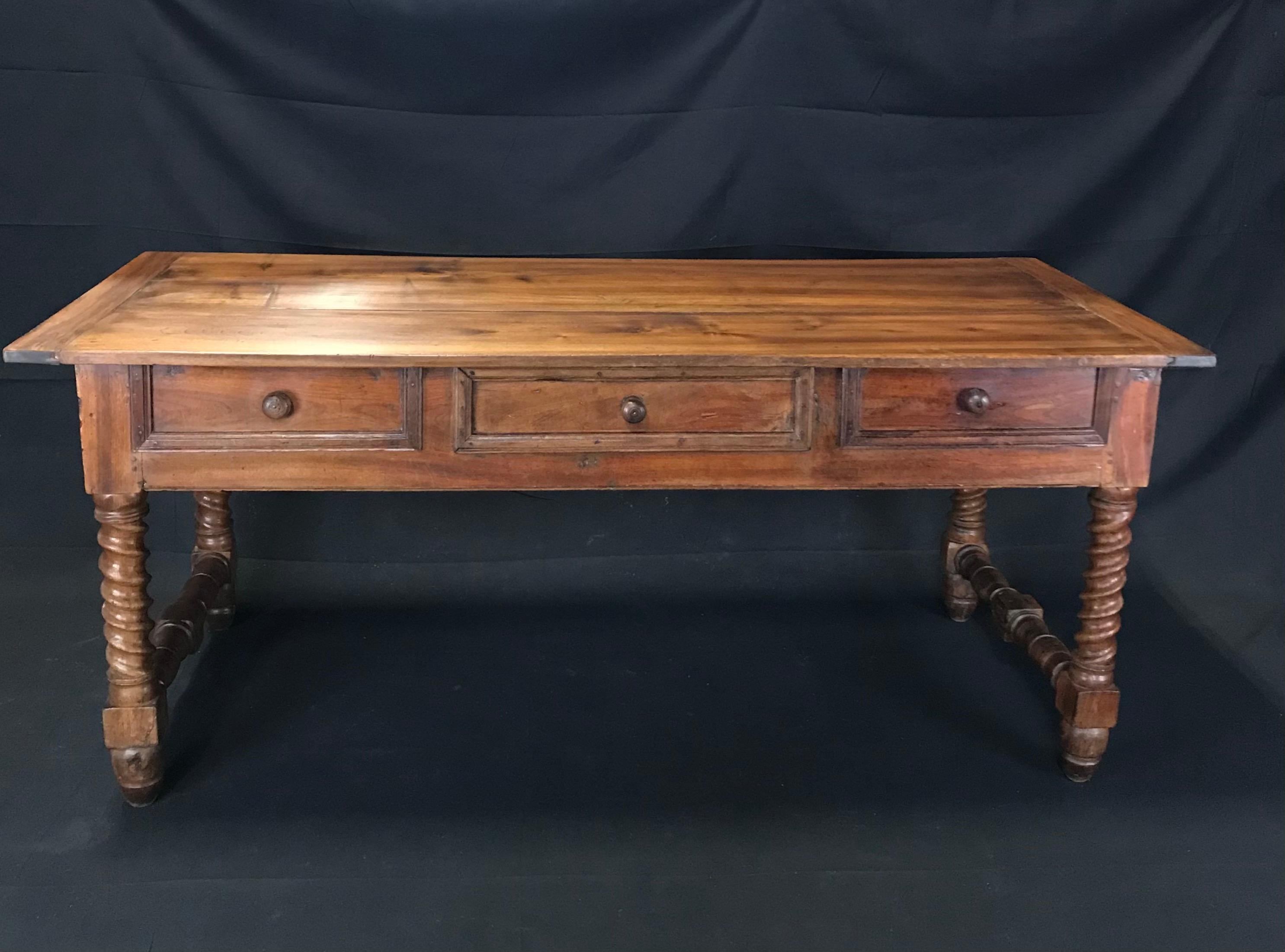 Handsome, rustic and sturdy French country walnut farm table with single center drawer and impressive barley twist legs. Beautiful solid two-plank top with breadboard ends on top of one center working drawer and four side molded faux drawers adds
