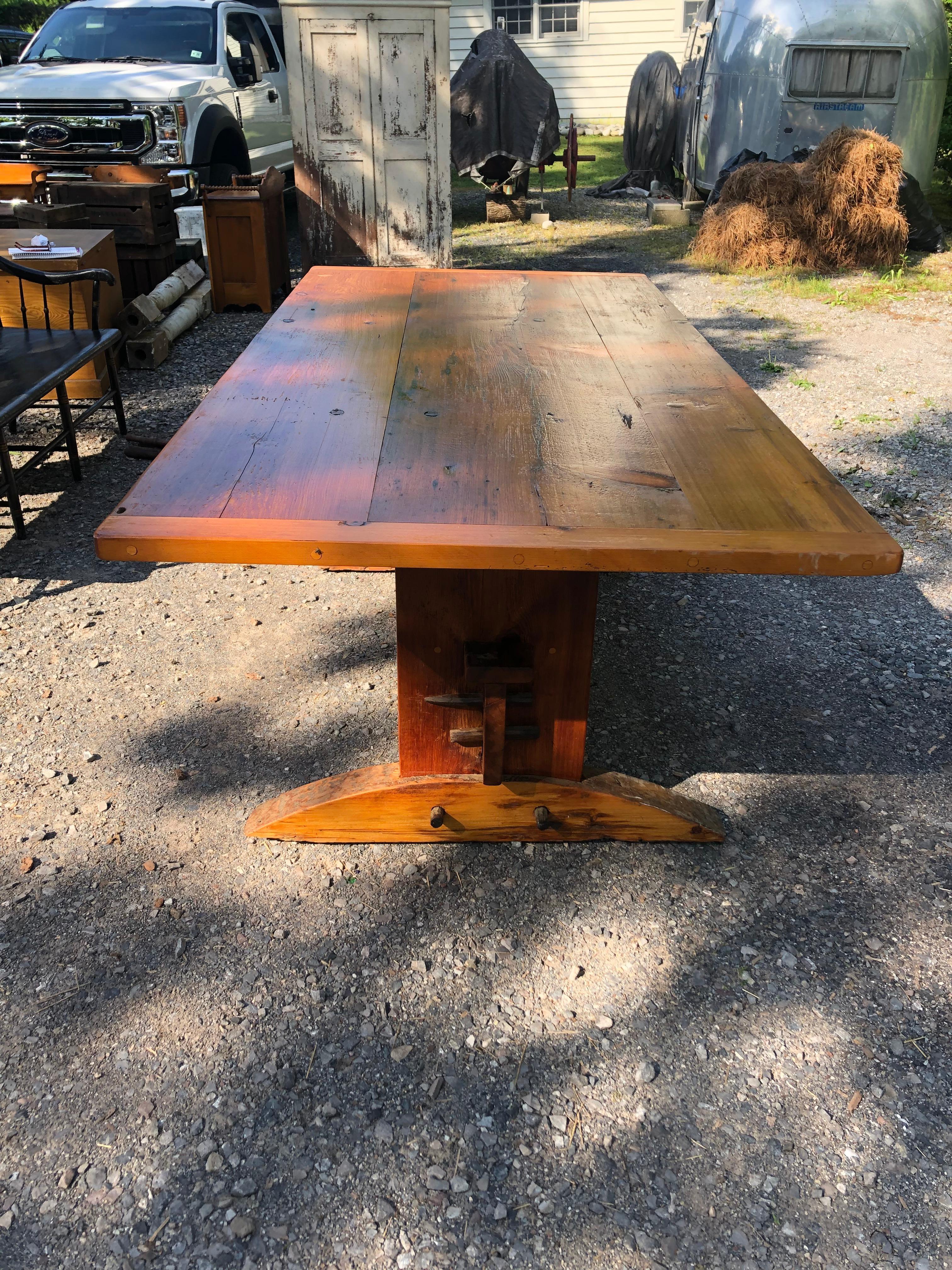 A large hand made rustic pine farm table oozing with character. Top is old reclaimed wood with knots and indigenous imperfections, base is hand hewn with bottom shelf and insertable pegs so the tabletop can be tilted upright and the piece transforms