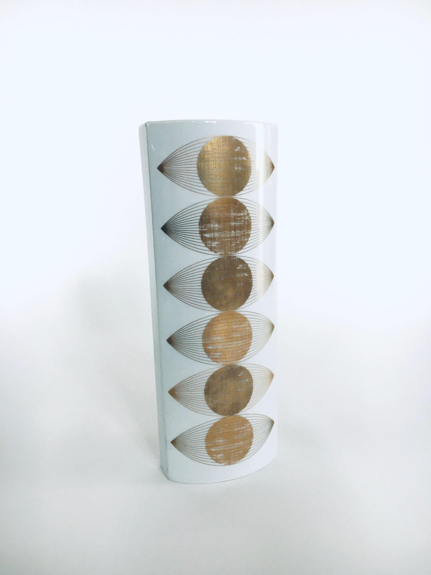 Vintage Op Art Porcelain Vase by E.A. Sundermann for Fürstenberg. Made in Germany 1960's / 70's period. White porcelain with gold sun eye print front and back. This comes in very good condition. Measures 32cm x 12cm x 7,5cm.