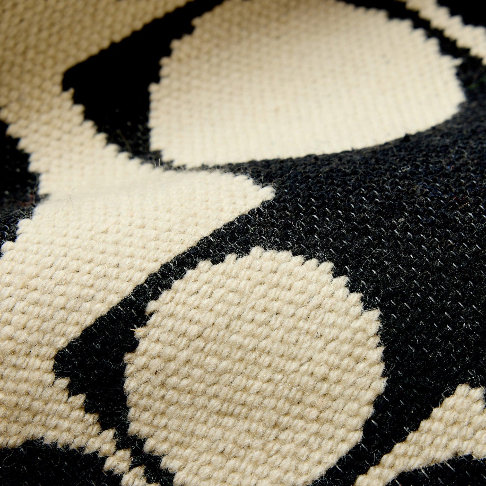 Un tappeto reversibile in stile Bauhaus con un motivo geometrico a cerchi bianchi e neri.