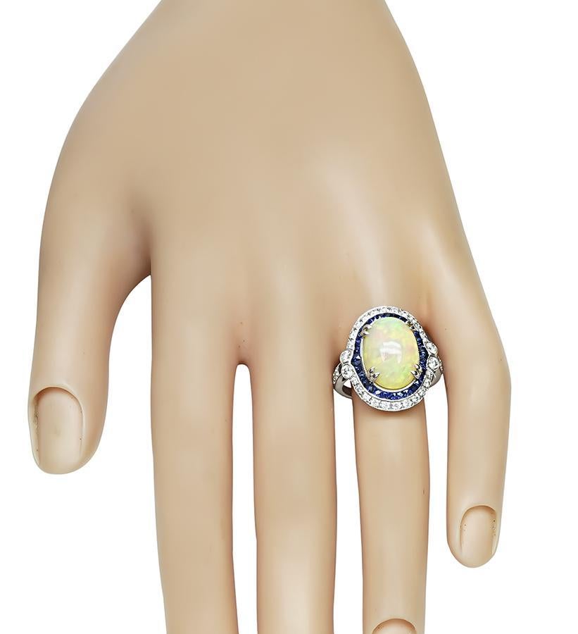 Dies ist ein fabelhafter Ring aus 18 Karat Weißgold. Der Ring ist mit schönen Cabochon Opal zentriert. Der Mittelstein wird durch funkelnde Diamanten im Rundschliff und französische Saphire mit einem Gewicht von ca. 0,60 ct bzw. 1,00 ct akzentuiert.