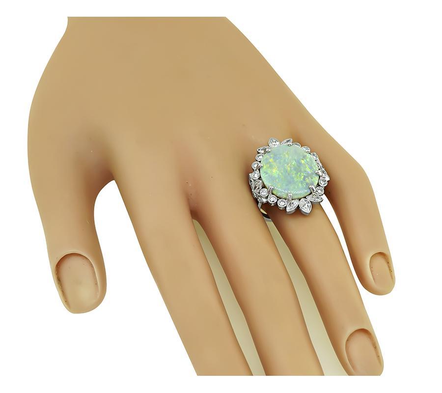 This is a charming 18k white gold ring. The ring is centered with lovely oval cut opal. The opal is accentuated by sparkling round and marquise cut diamonds that weigh approximately 2.00ct. The color of these diamonds is G-H with VS clarity. The top
