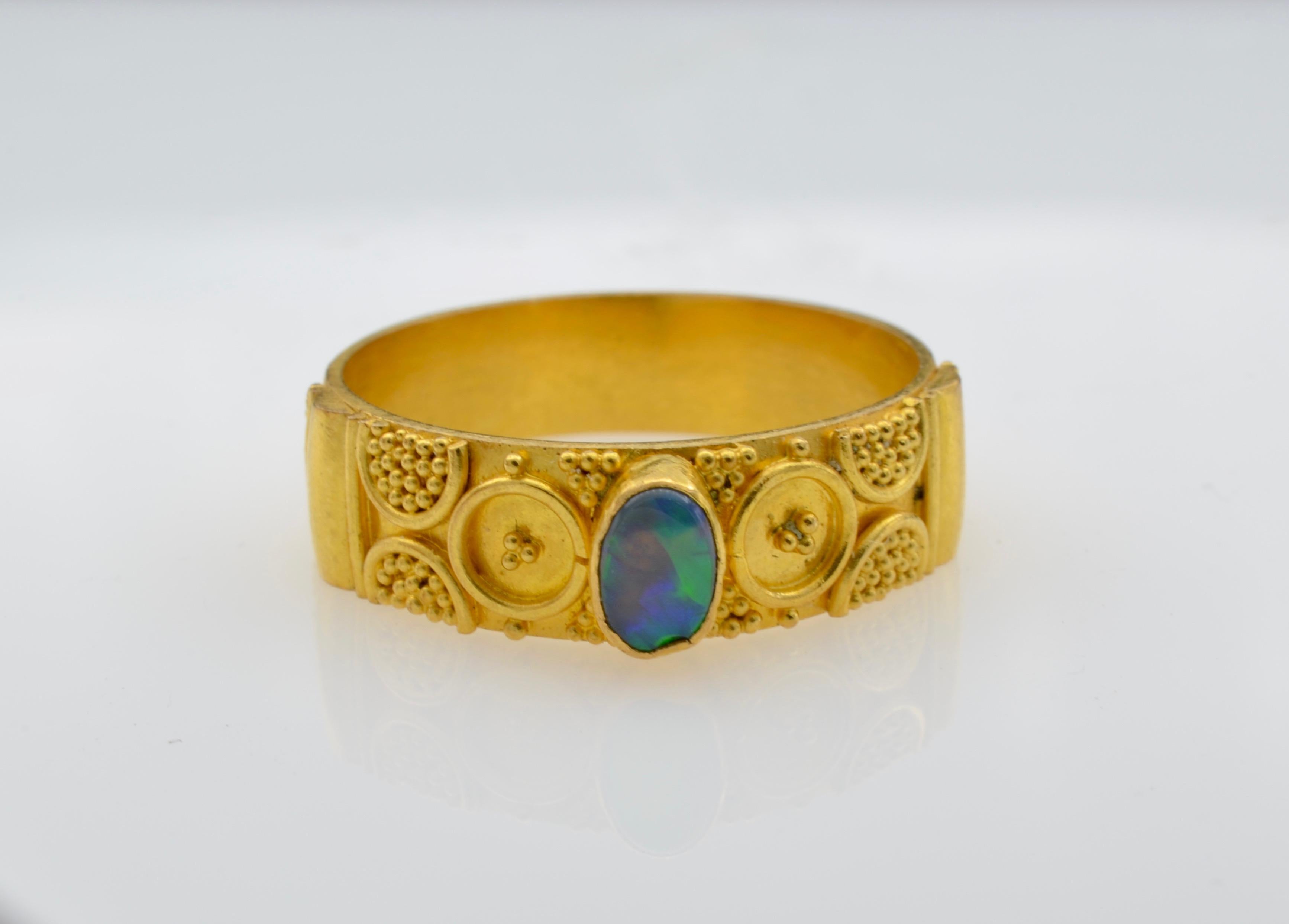 This simple and stunning 22k gold band has a whimsical granular design. The bright yellow of the 22 k gold beautifully accents the oval opal. The ring is a size 6 1/2 and can be sized to fit your finger.