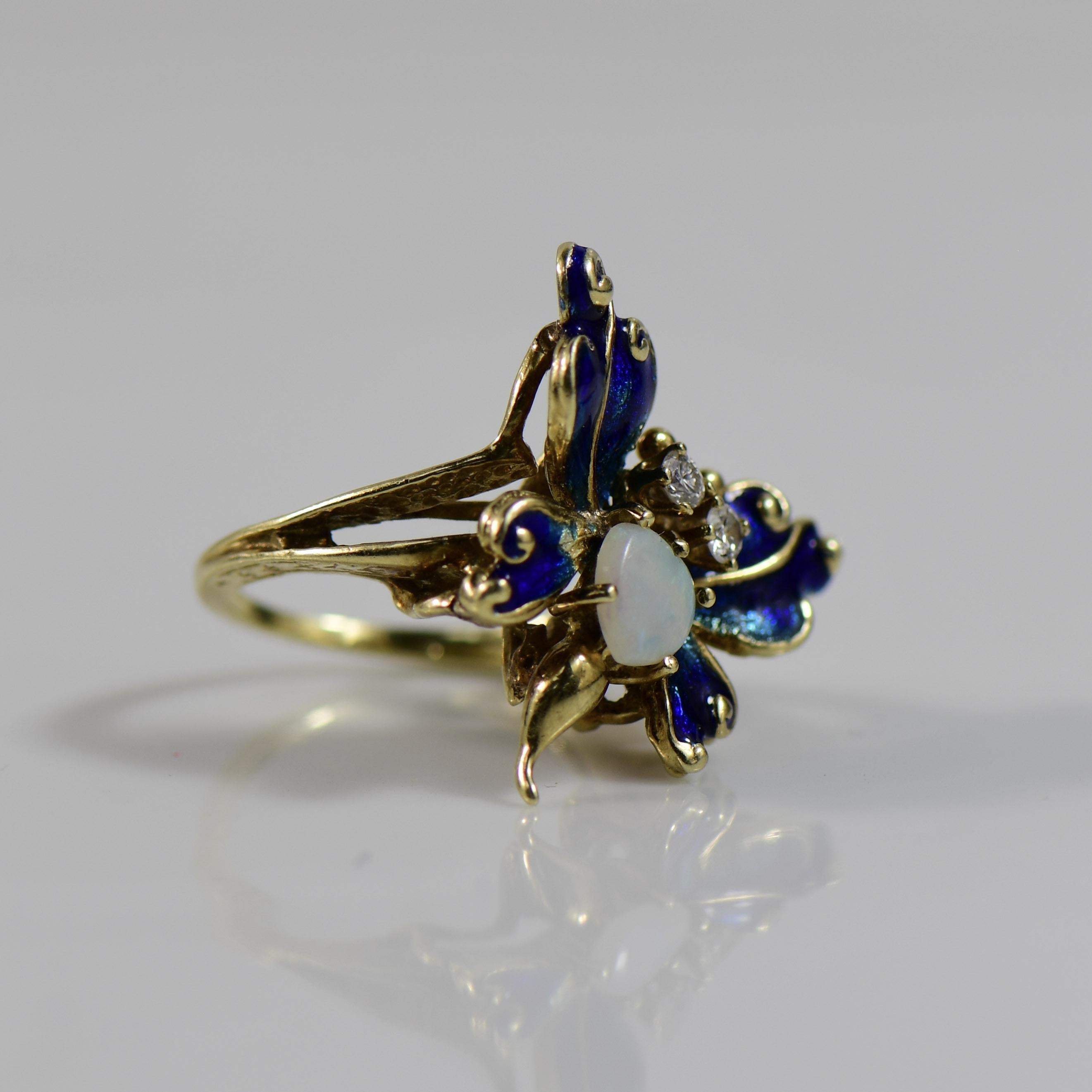 Adorn your fingers with whimsical charm through this vintage blue enamel butterfly ring, featuring a heart-cut opal center that radiates with ethereal hues. The delicate craftsmanship of the butterfly's wings, intricately adorned with blue enamel,