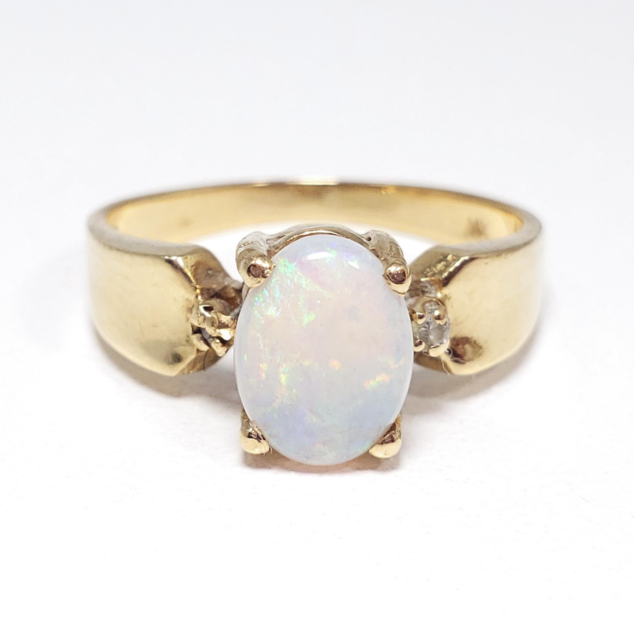 A stylish minimalist ring featuring a precious white-body opal accented with two .01ct diamonds on each side, set on a tapered 14K gold band. Beautiful play-of-color in the opal, which is prong-set in an elevated setting.

Ring Size: US 6
Opal