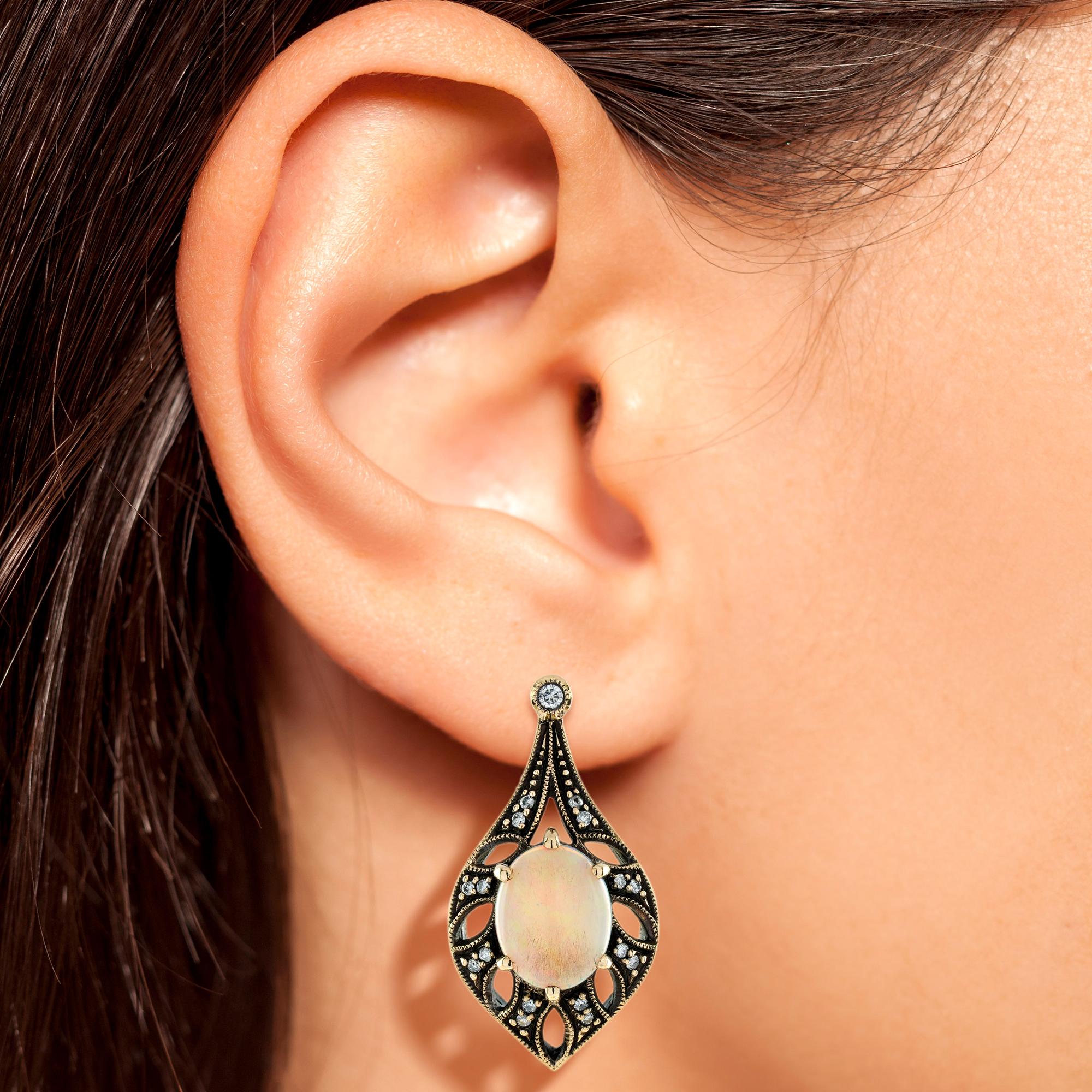 Dies ist ein exquisites Paar Opaltropfen-Ohrringe im Vintage-Design. Die Ohrringe haben ein durchbrochenes Design mit ovalen Opalen in der Mitte, die von schönen, funkelnden Diamanten umgeben sind. Alle Ohrringe sind aus 9 Karat Gelbgold. 

Ohrringe