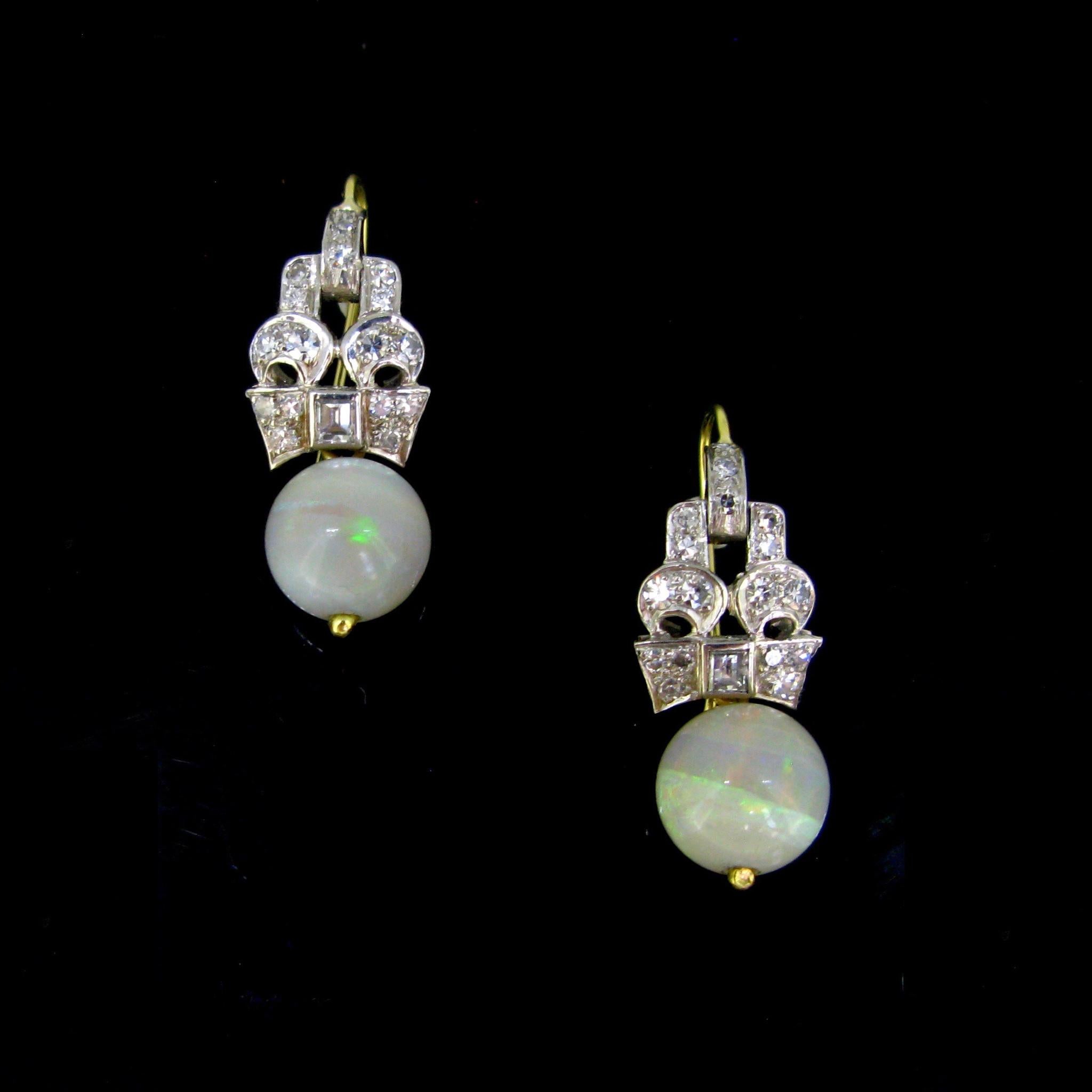 These ravishing dangling earrings are adorned with lively and coloured natural opals and diamonds. The opals have nice fires. The mount is made in platinum and set with single cut diamonds and a square cut diamonds. There is an approximate total