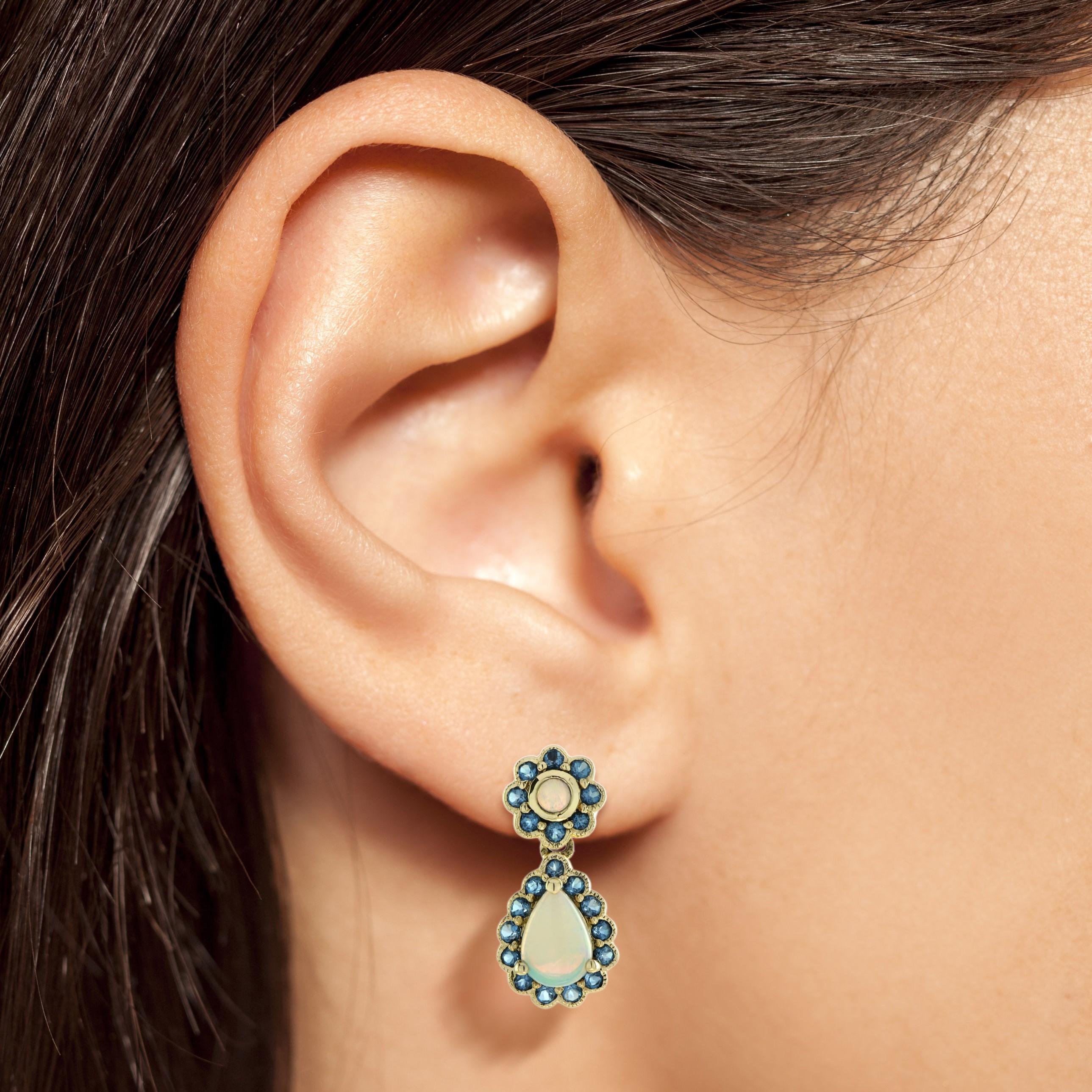 A lovely pair of Victorian design drop earrings, each set to the top with an opal within a frame of London blue topazes suspending a pear shaped opal drop in 9k gold collect setting. A charming pair of earrings that can be worn in