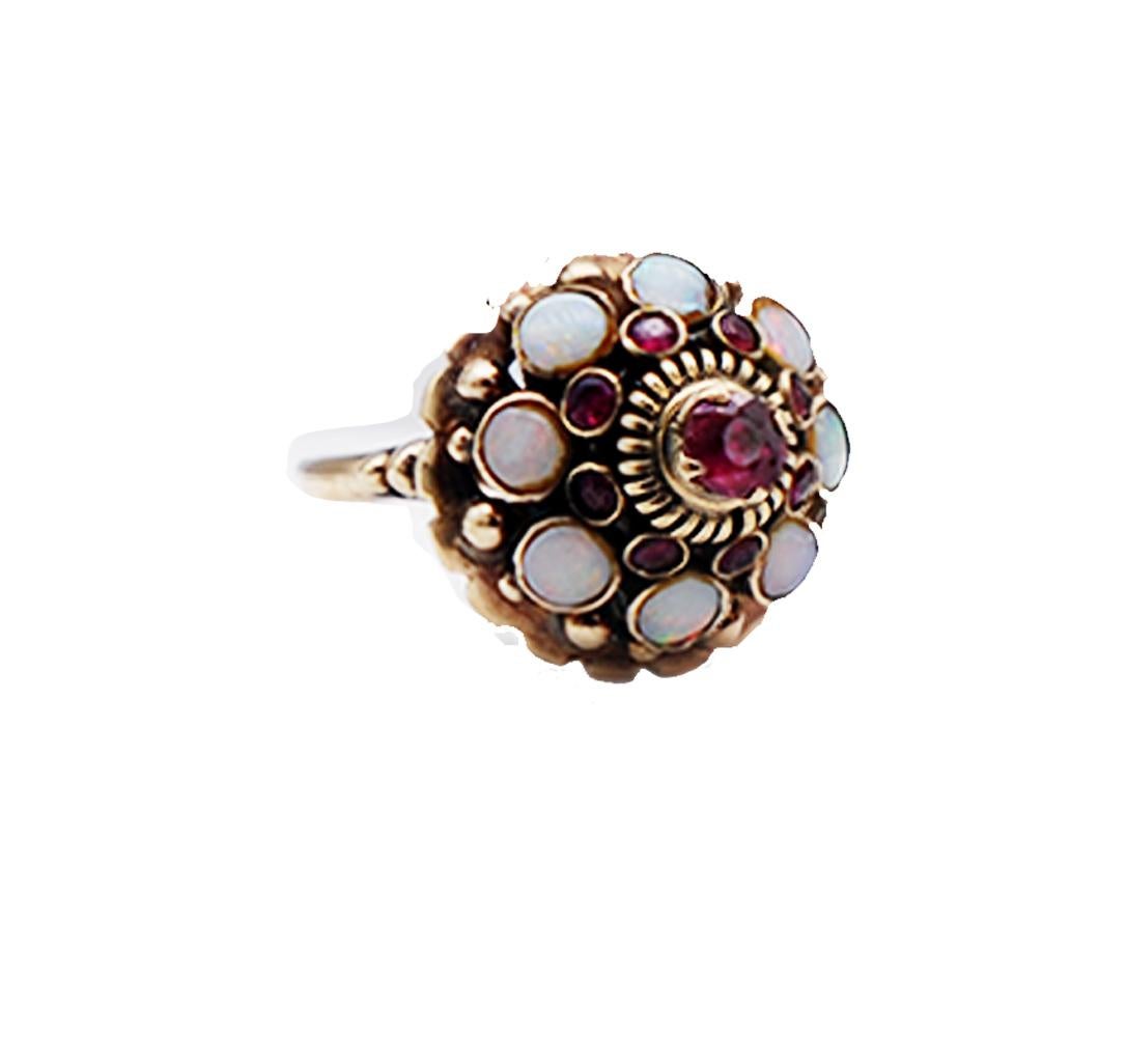 Antique Temple, ring is colorful and tall measuring 17mm tall by 16 mm wide. The ring is mostly hand made with 8- round fire colored opals (3.55mm) and 8 rubies (1.80-3.65mm). The detail of bezel setting and textured rope edging make this ring