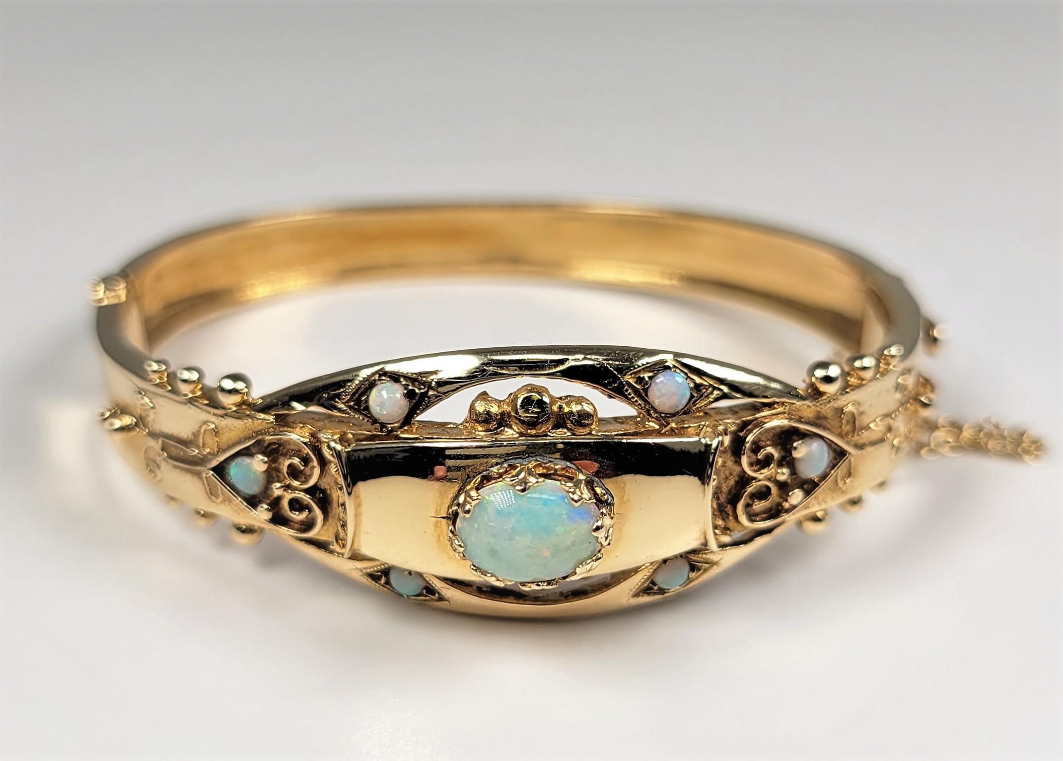 14 Karat yellow gold bangle with opal center stone and opal accents.  This charming bracelet is from the 1950's.