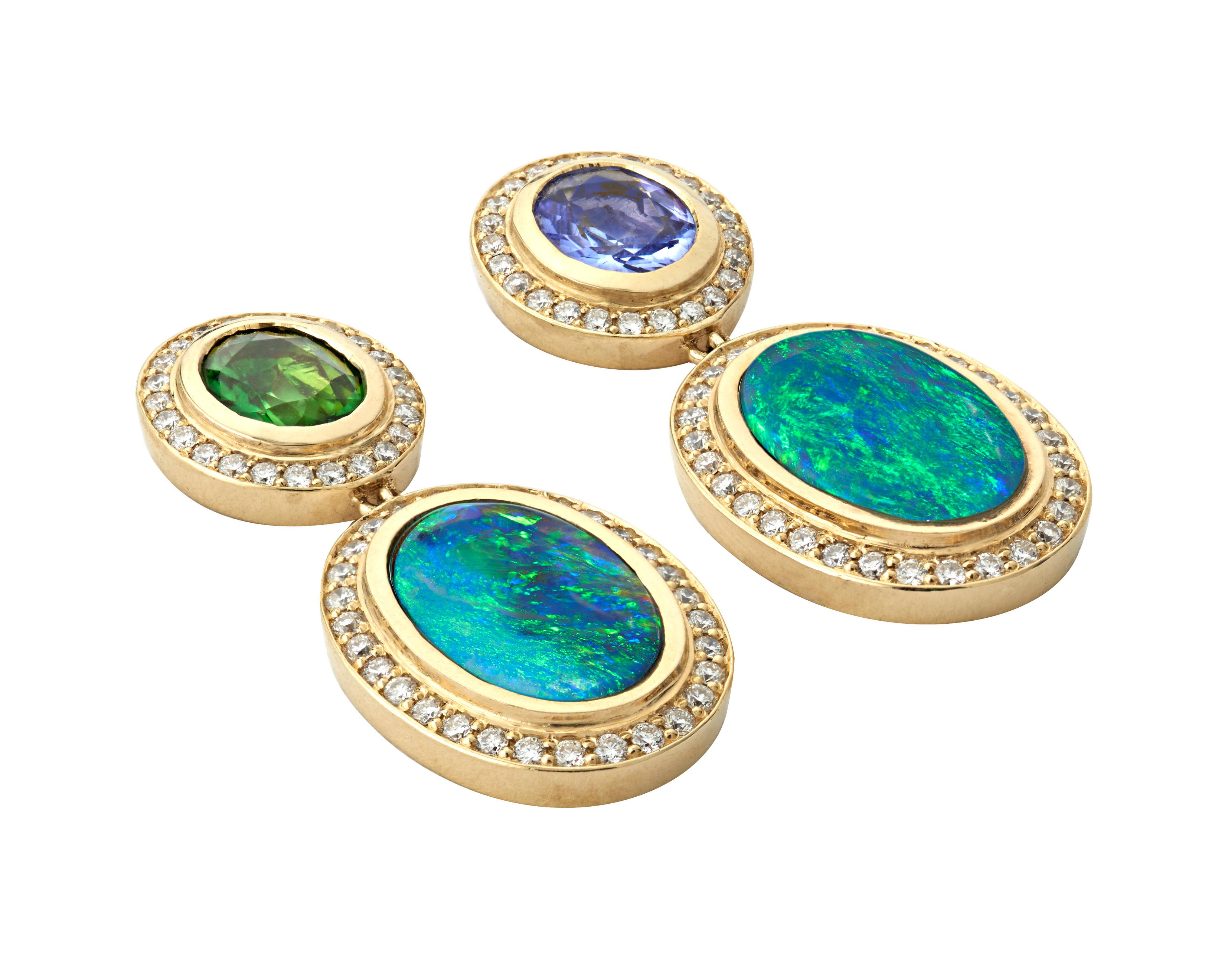 These award winning, 18k yellow gold drop earrings featuring two deep aqua black opal cabochons. One post showcasing a faceted oval Tanzanite gemstone and the other post sporting a beautiful oval Tsavorite gemstone.  This modern design using a